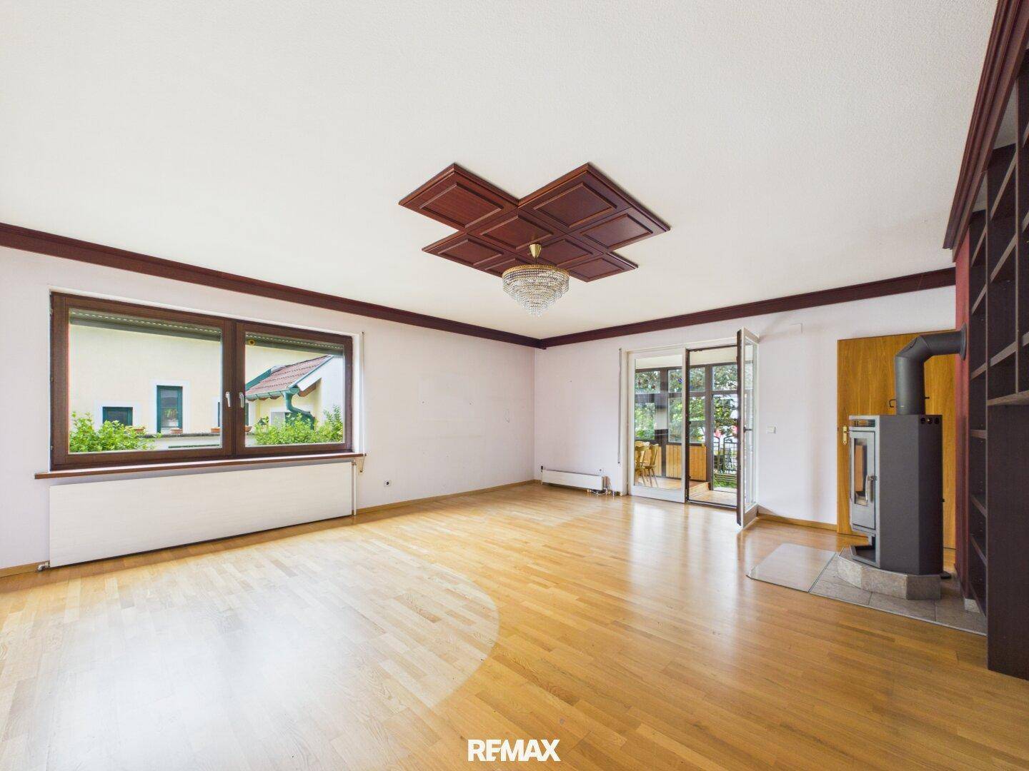 Helles Wohnzimmer mit Holzboden, Kaminofen und Zugang zu einem Balkon.