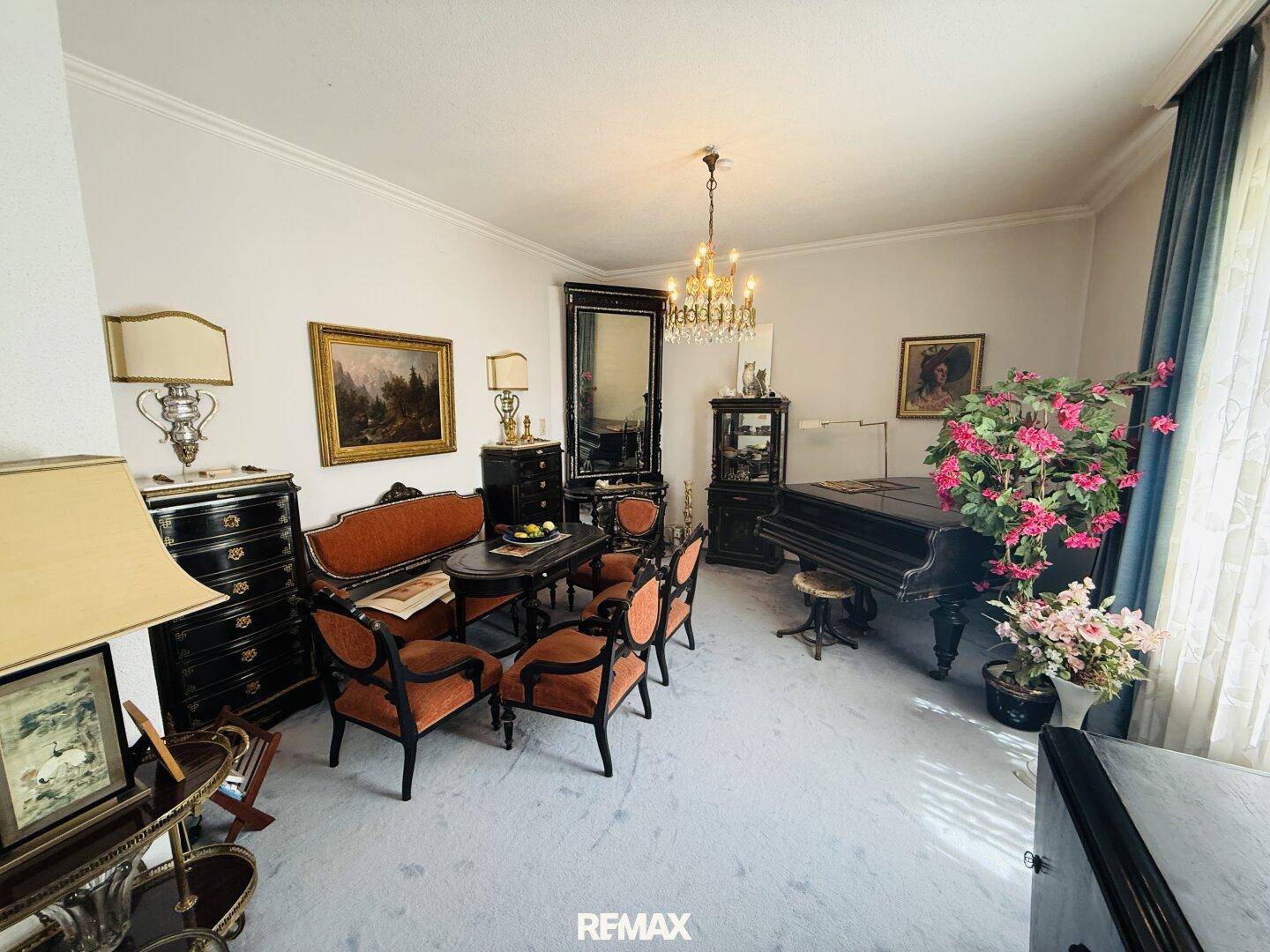 Elegantes Wohn- und Esszimmer mit antikem Mobiliar, Kronleuchter und Klavier.