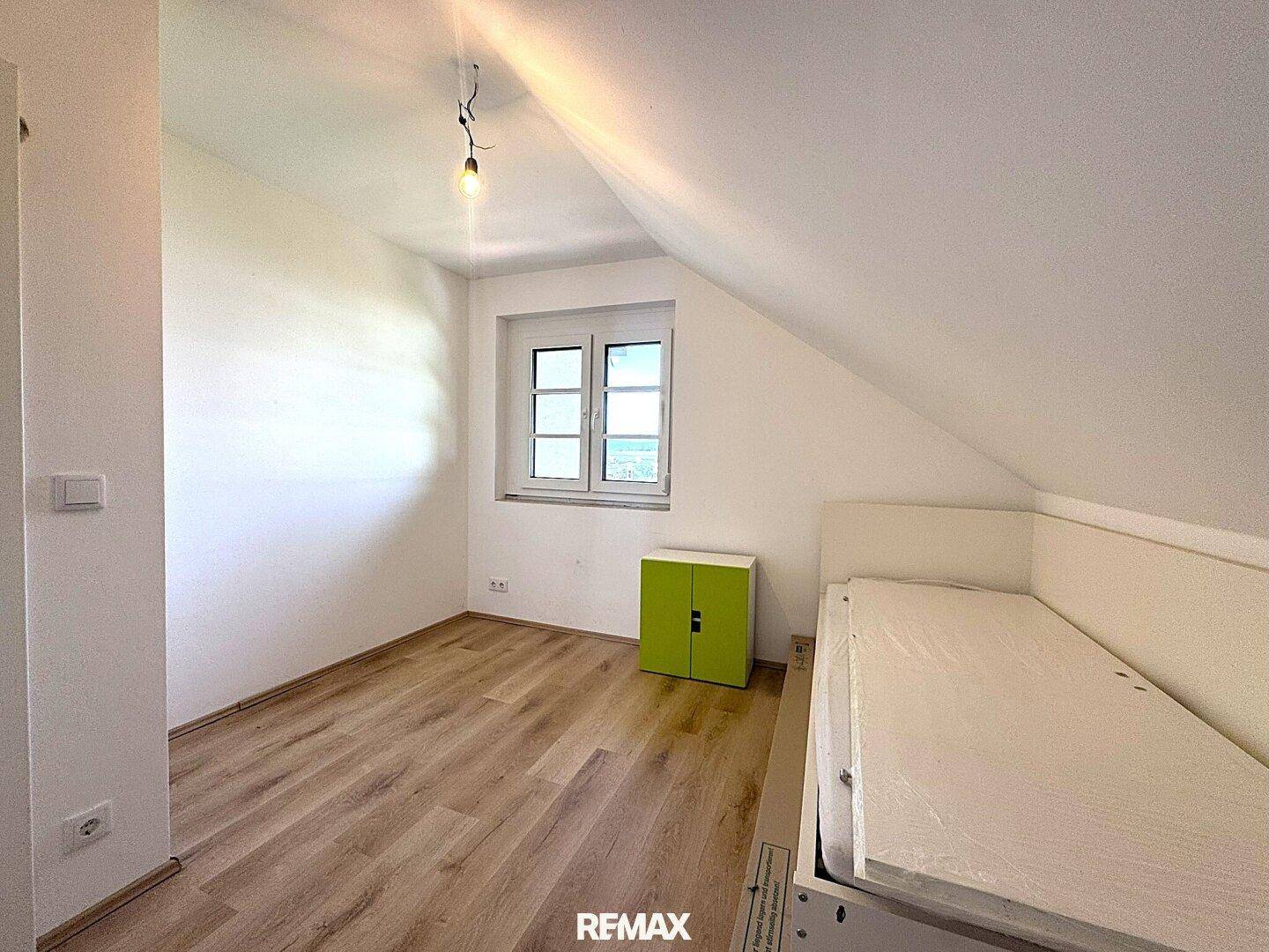 Gemütliches Schlafzimmer im Dachgeschoss mit Laminatboden und einem Fenster.