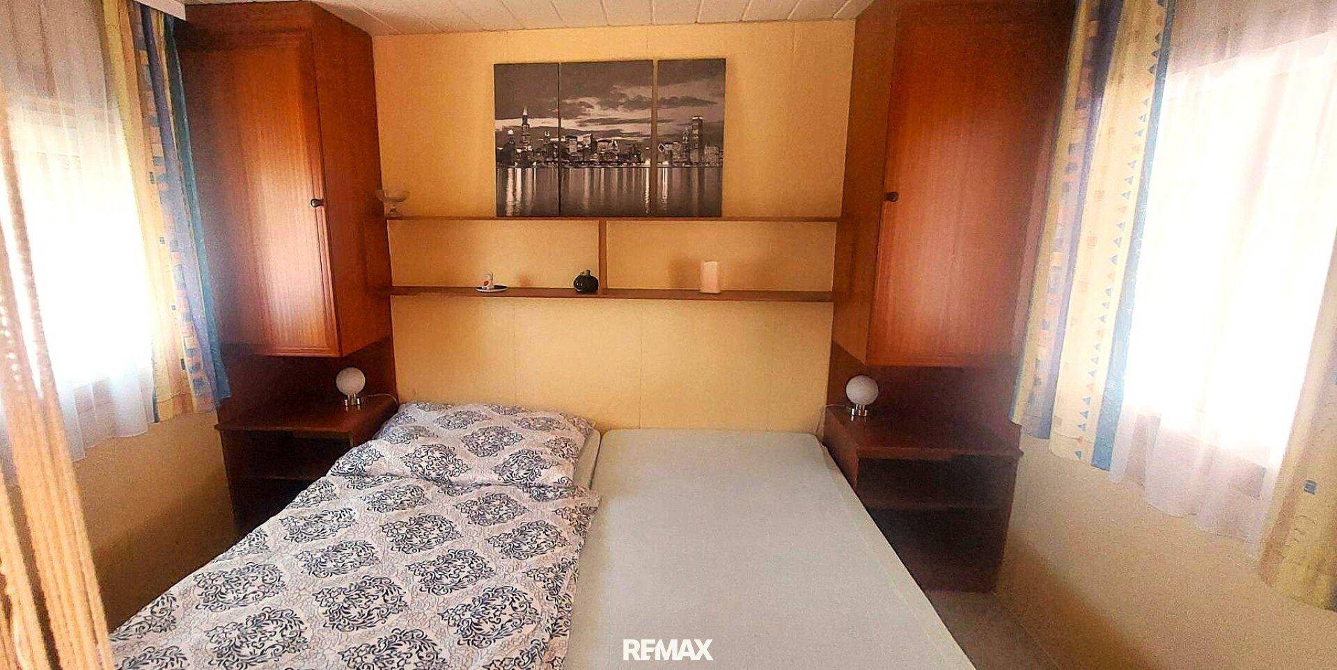 Schlafzimmer mit Einzelbett, Nachttischen und praktischen Einbauschränken.