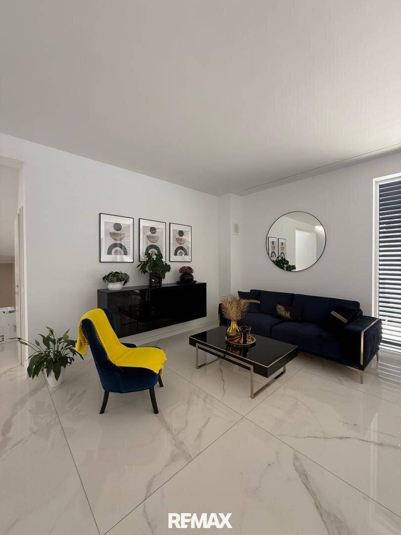 Gemütlicher Wohnbereich mit dunklem Sofa, gelbem Akzentsessel und moderner Wanddekoration.