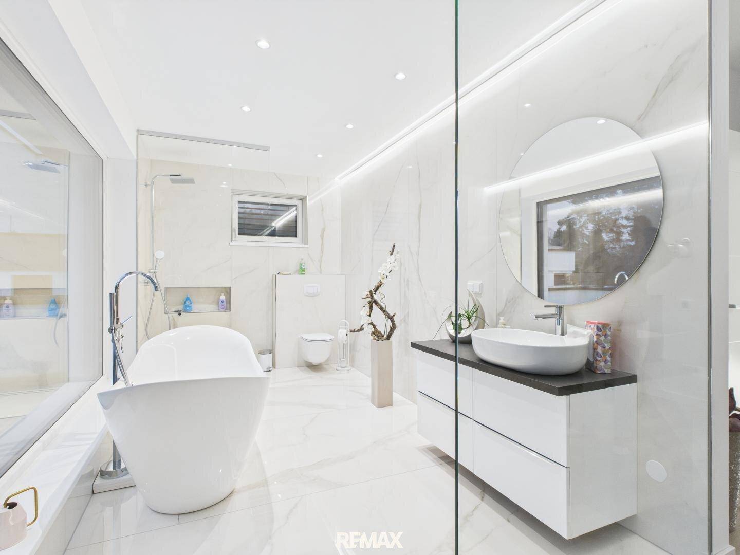 Luxuriöses Badezimmer mit freistehender Badewanne, Doppelwaschbecken und Marmorfliesen.