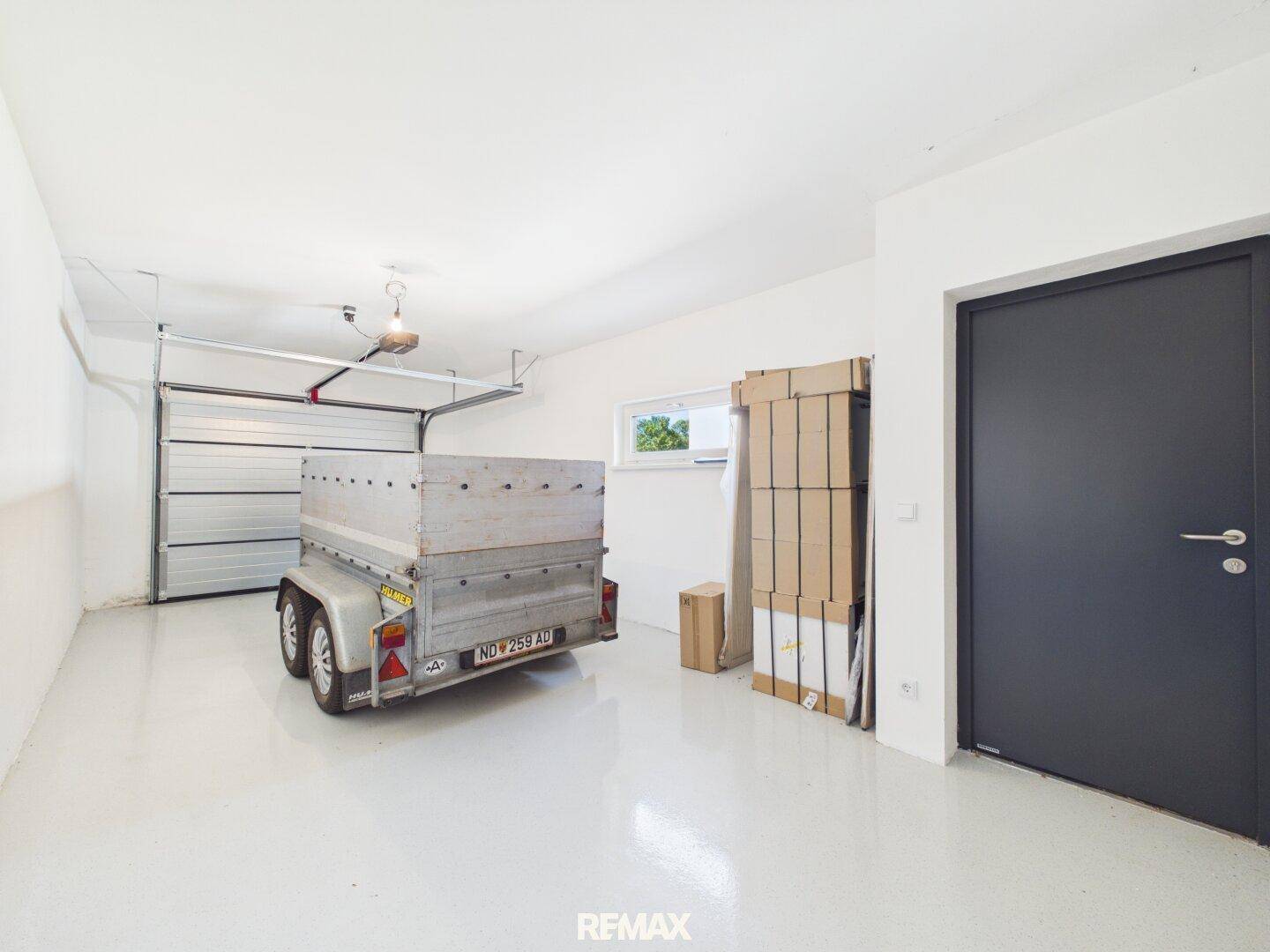 Geräumige Garage mit einem Anhänger, Lagerkartons und einem Fenster.