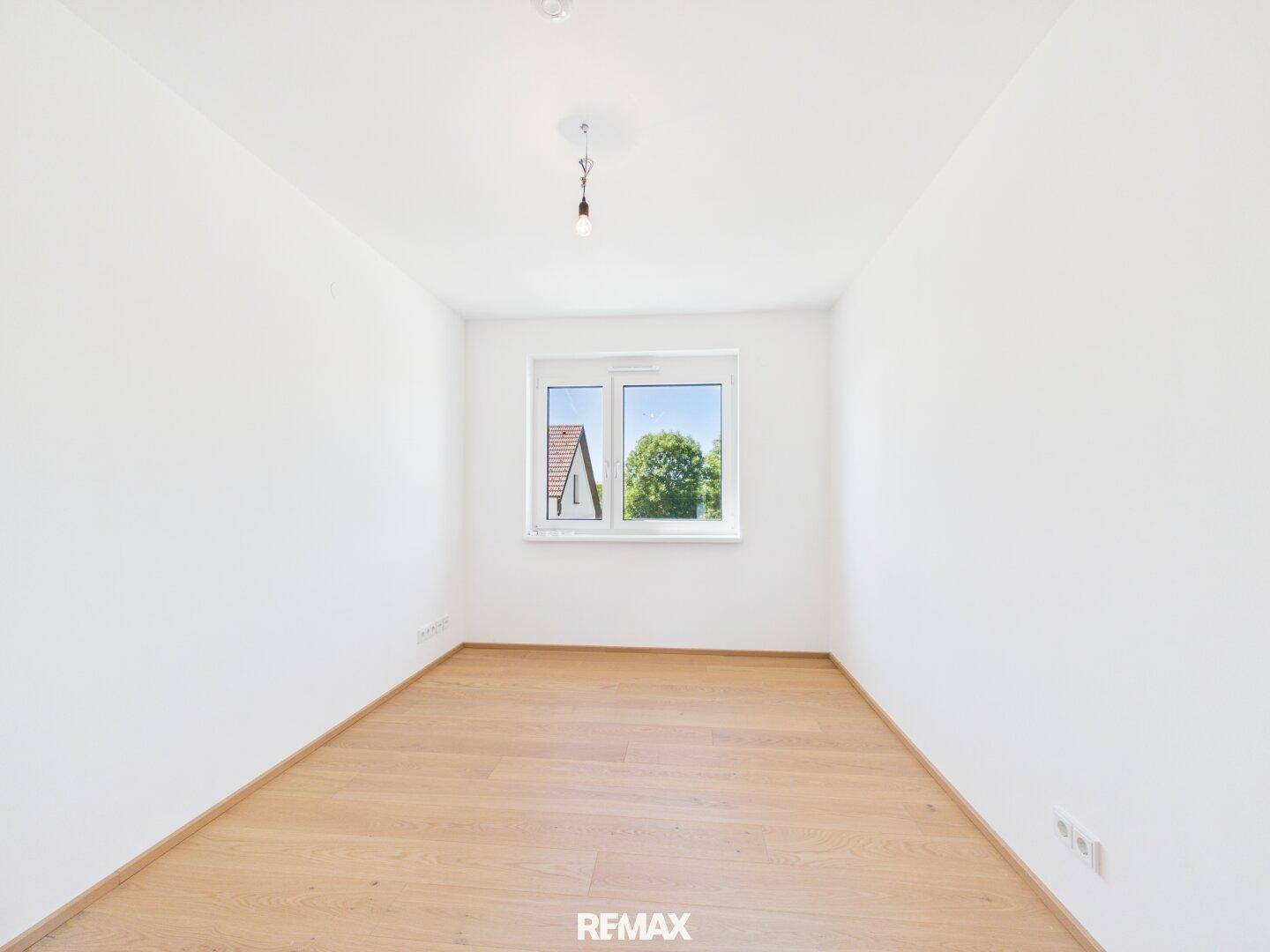 Helles Schlafzimmer mit Eichenparkettboden und einem großen Fenster mit Ausblick.