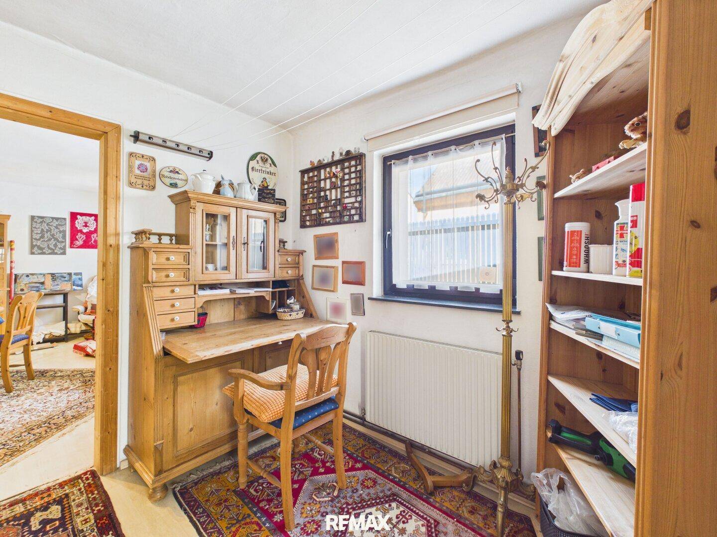 Kleiner Arbeitsbereich mit antikem Holzschreibtisch, Bücherregal und Fenster.