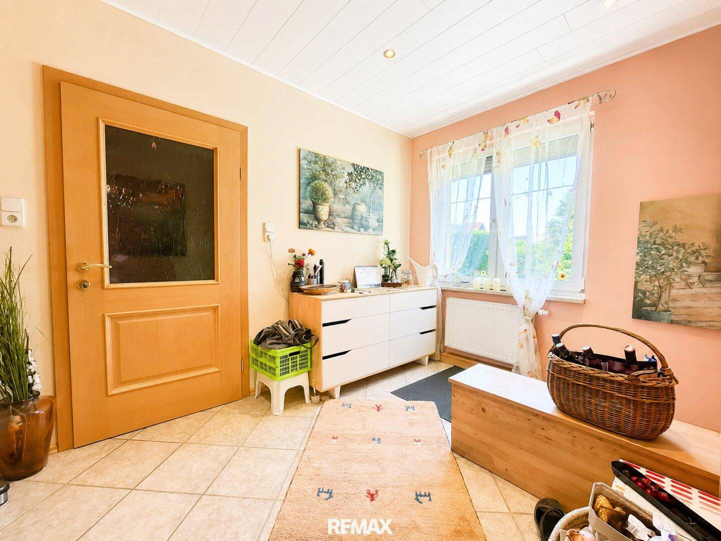 Helles Zimmer mit Fenster, Kommode und Teppich, ideal als Büro oder Gästezimmer.