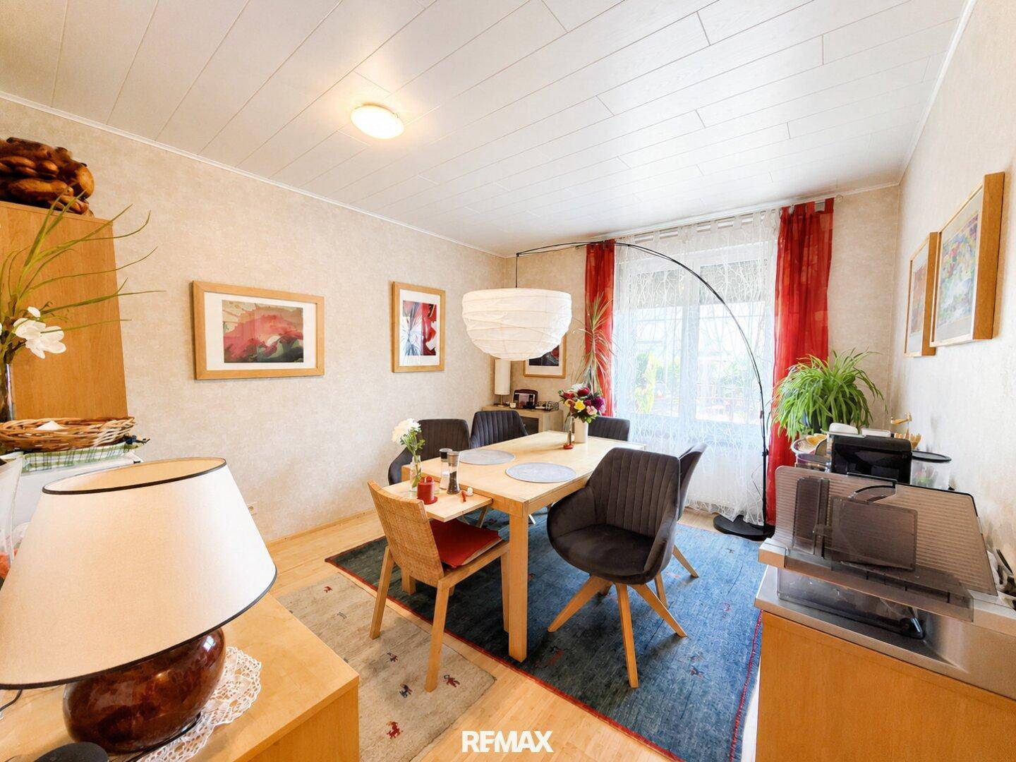 Gemütliches Esszimmer mit Holztisch, modernen Stühlen und großem Fenster.