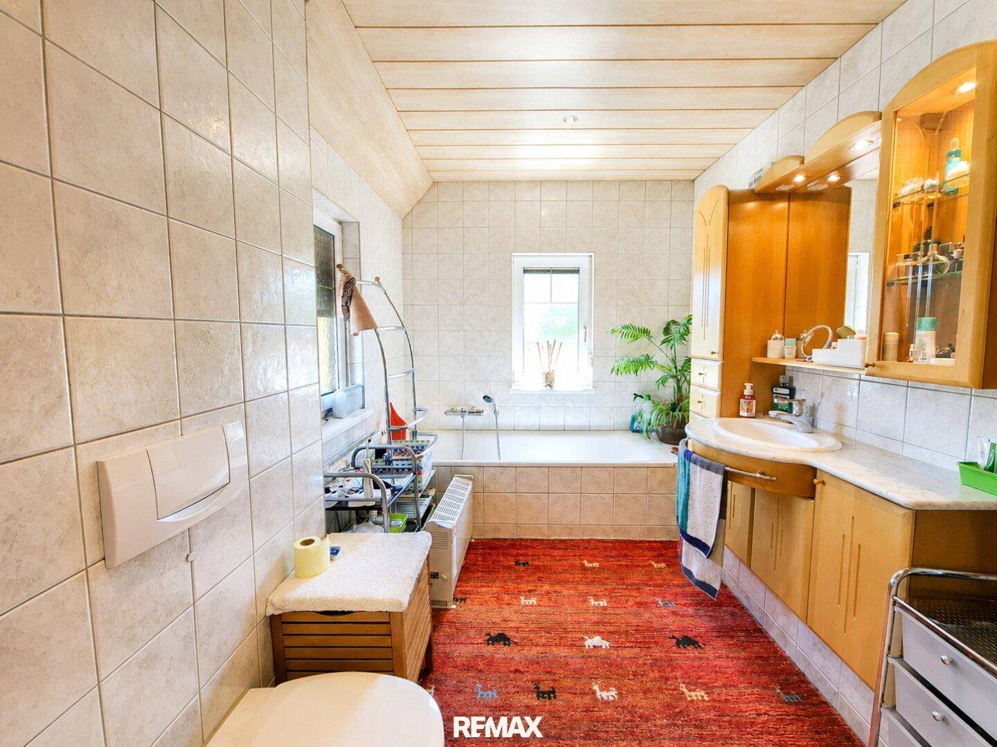 Geräumiges Badezimmer im Dachgeschoss mit Badewanne, Waschbecken und hellen Fliesen.