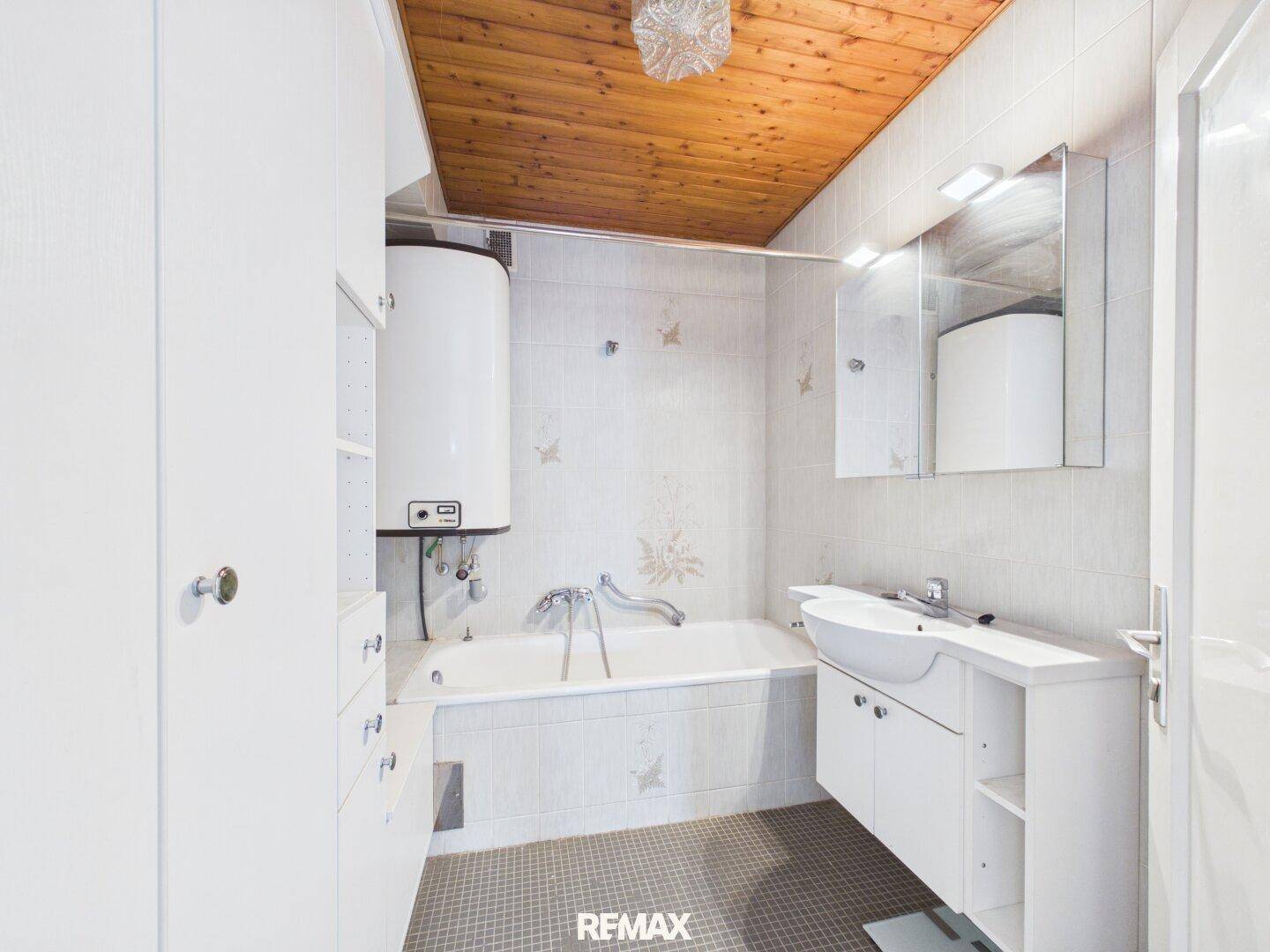 Badezimmer mit Badewanne, Waschbecken und Holzdecke in hellem Design.