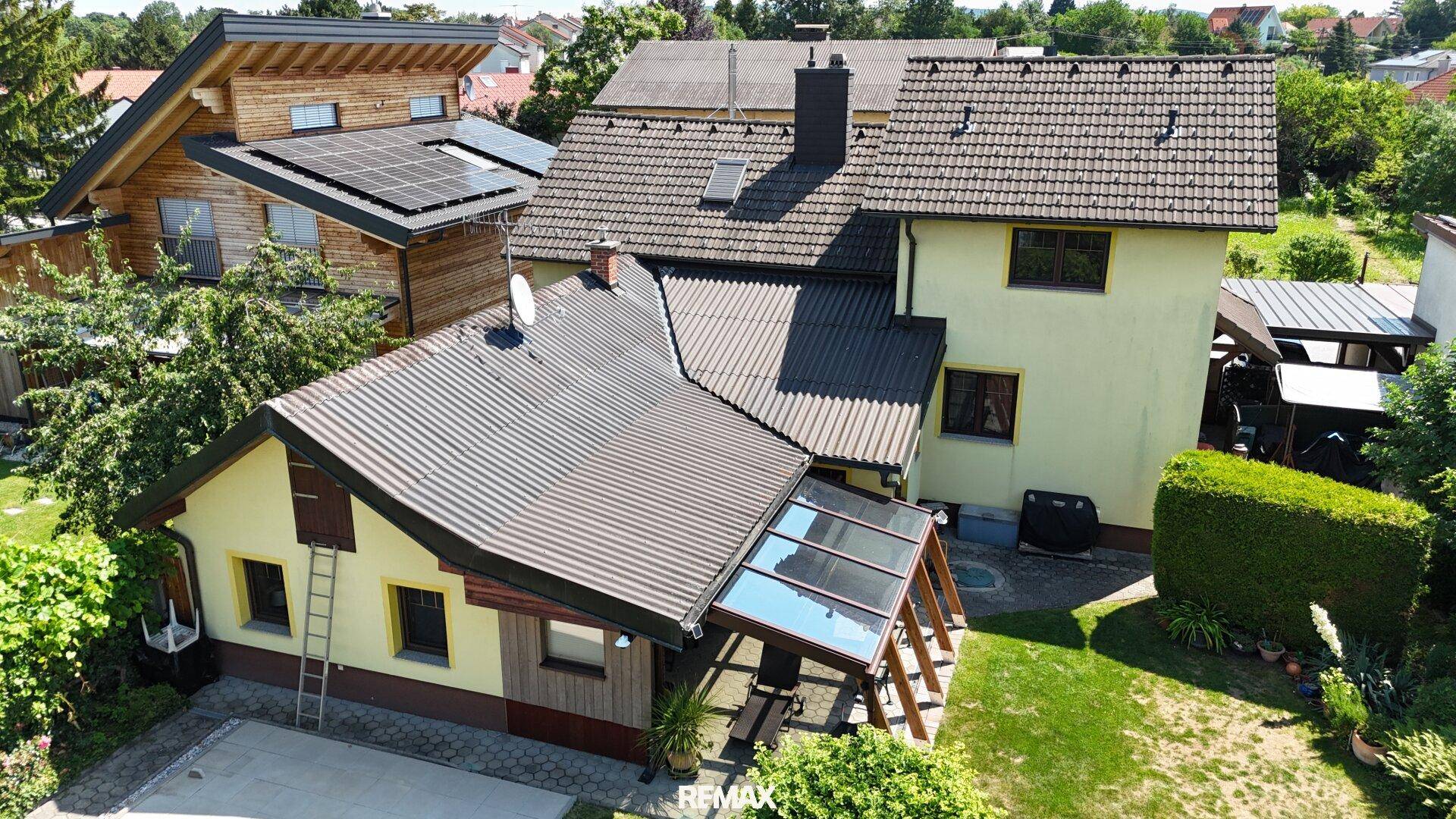 Luftaufnahme des Hauses mit Garten und angrenzenden Gebäuden in einer grünen Umgebung.