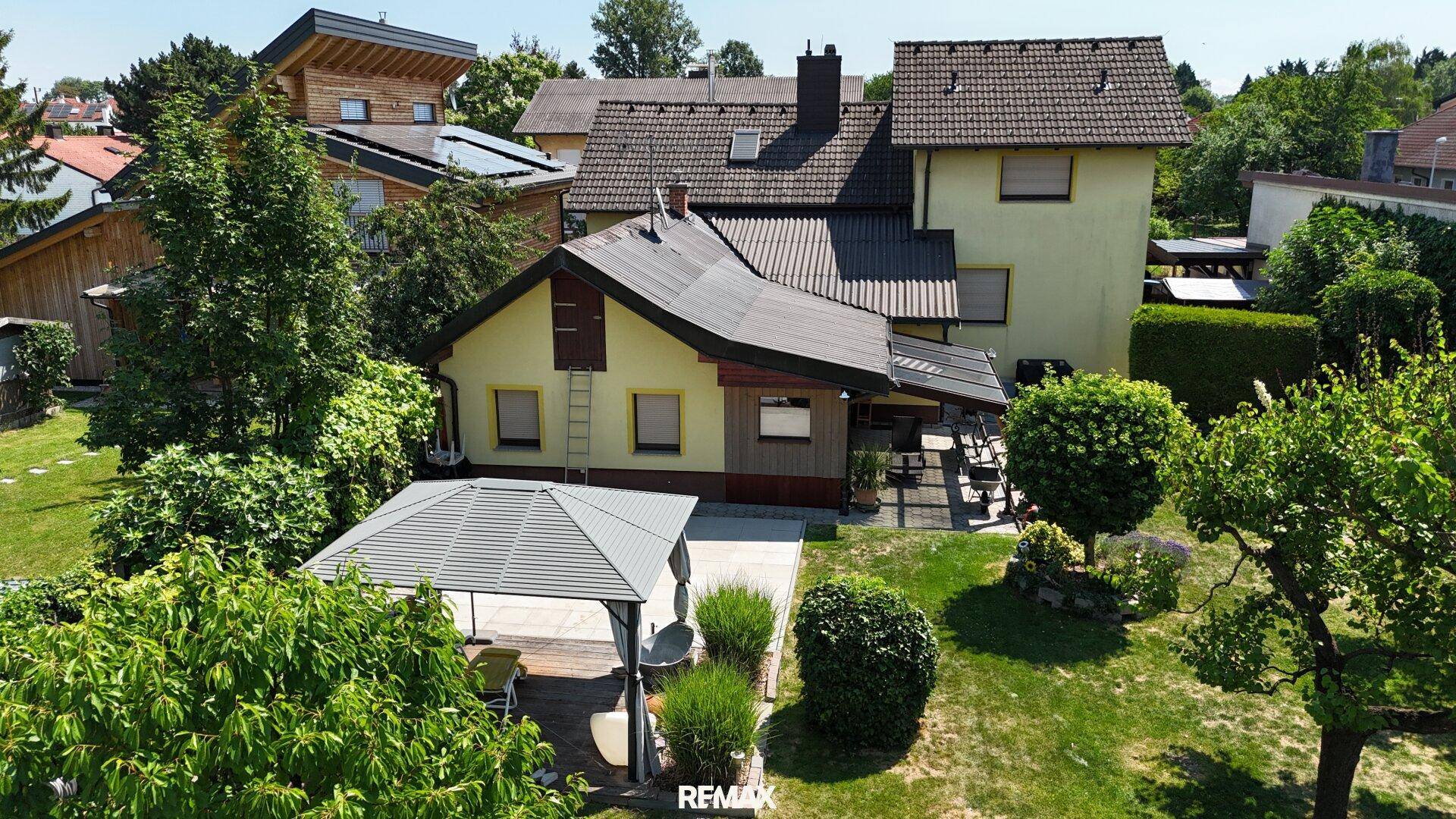 Gepflegter Gartenbereich mit Pavillon, Rasenfläche und altem Baumbestand rund um das Haus.
