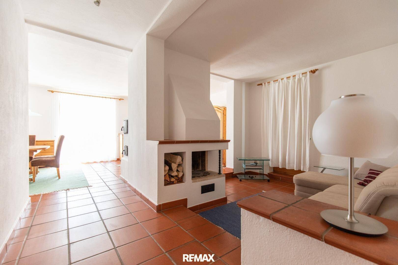 Gemütliches Wohnzimmer mit Kamin und Terrakottafliesen, offen zum Essbereich.