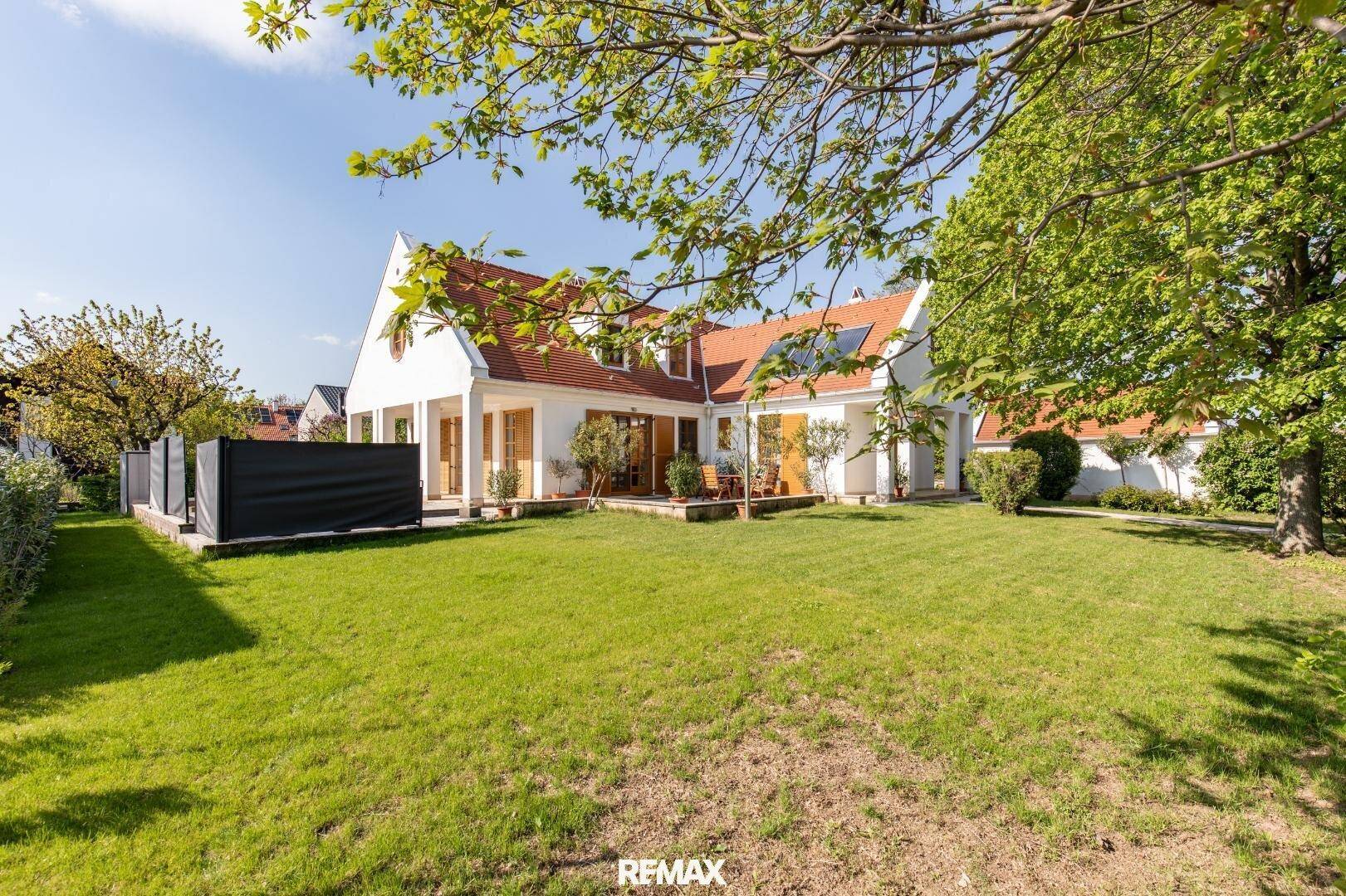 Weitläufiger Garten mit gepflegtem Rasen und Blick auf die Rückseite des Landhauses.
