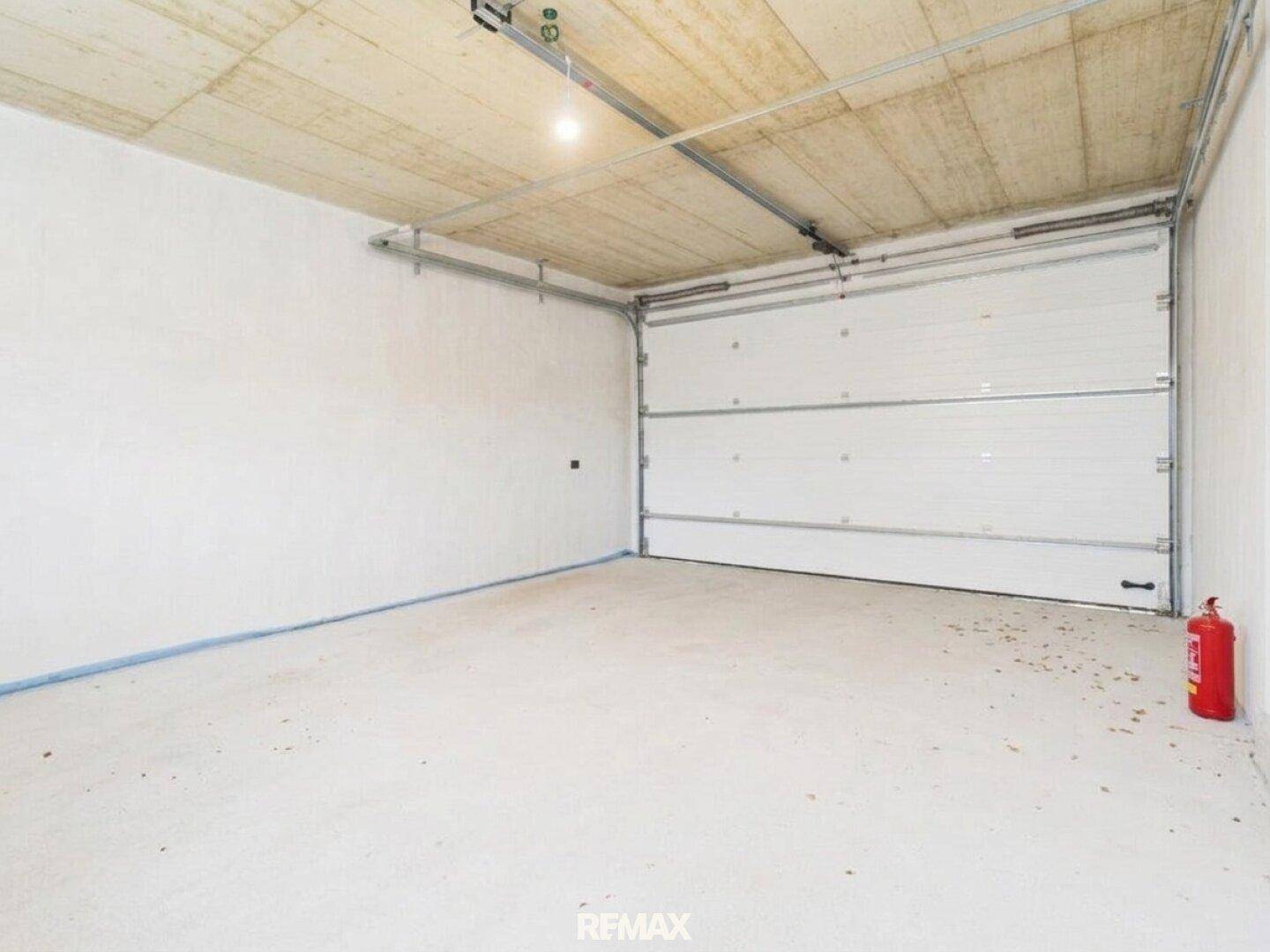 Geräumige Garage mit Betonboden und großem Sektionaltor, bereit zur Nutzung.