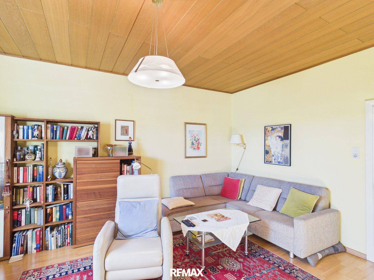 Wohnzimmer mit Ecksofa, Bücherregal und Holzdecke, ideal zum Entspannen.