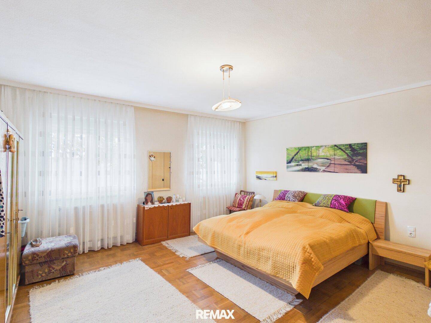 Helles Schlafzimmer mit Doppelbett, Holzmöbeln und Parkettboden.