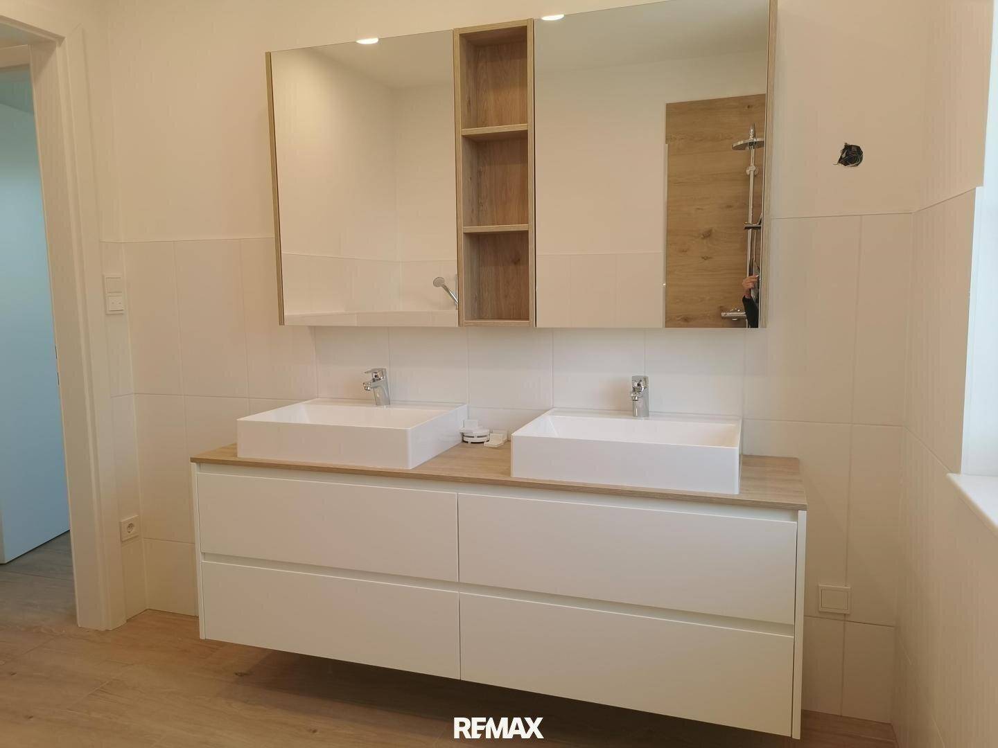 Modernes Badezimmer mit Doppelwaschbecken, großem Spiegelschrank und Holzdetails.
