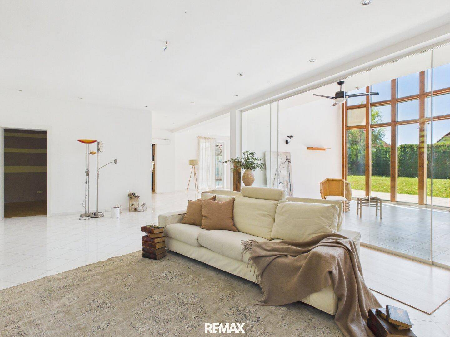 Helles und geräumiges Wohnzimmer mit großen Fenstern und Blick ins Grüne.