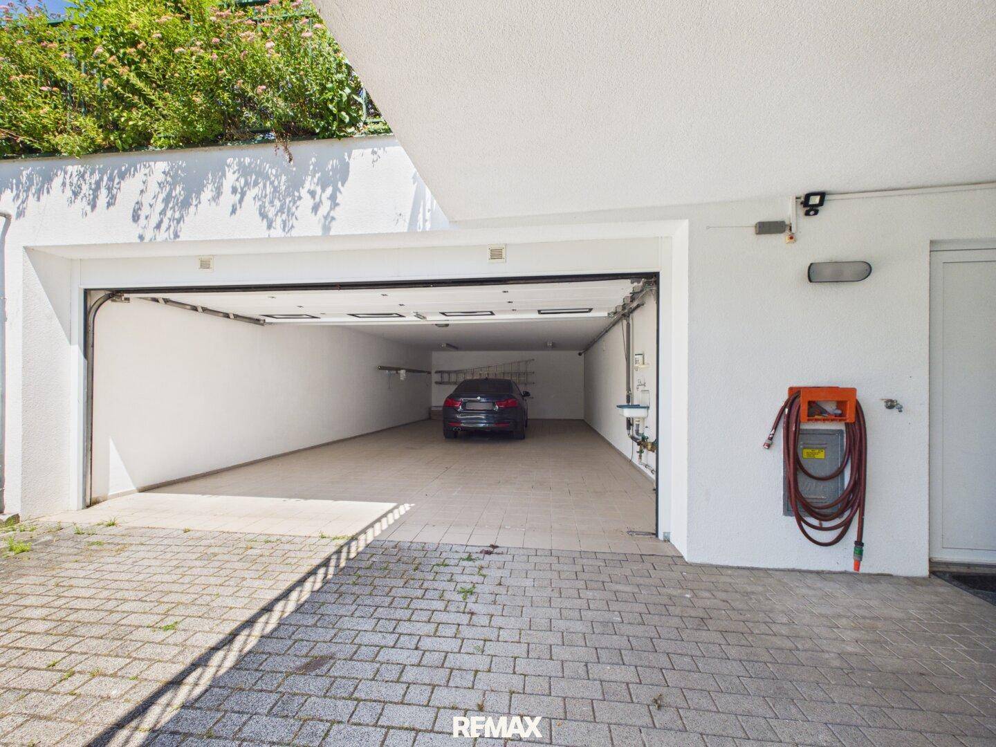 Geräumige Doppelgarage mit offenem Tor und einem Fahrzeug, umgeben von gepflegter Außenanlage.