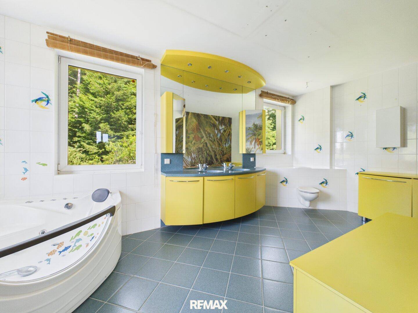 Geräumiges Badezimmer mit Whirlpool, Doppelwaschbecken und Fenstern zum Garten.