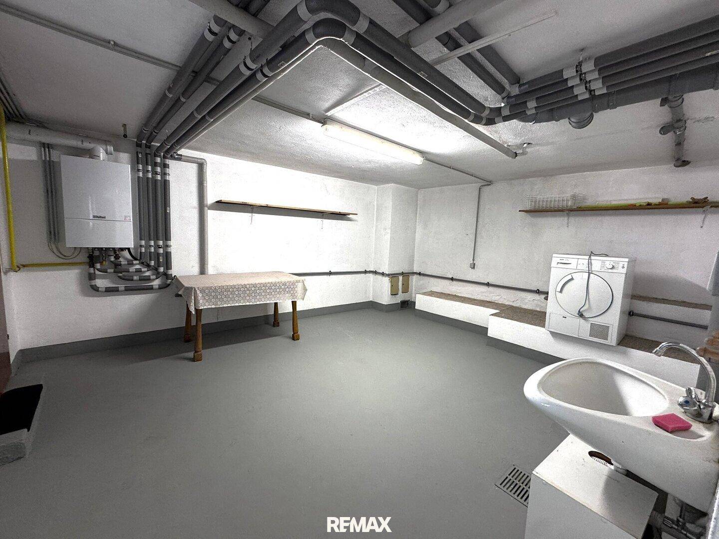 Hauswirtschaftsraum im Keller mit Waschmaschine, Trockner und Waschbecken.