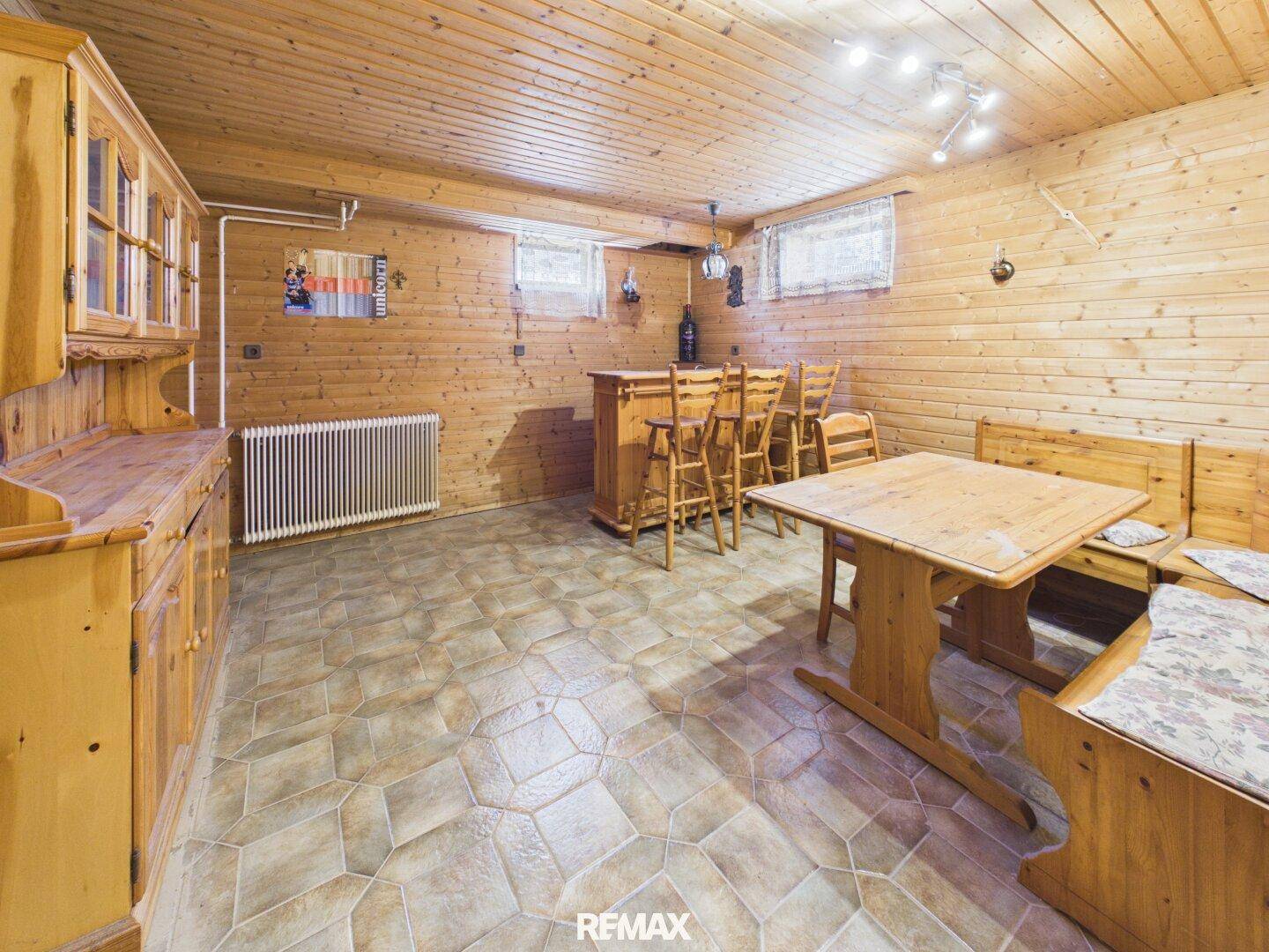 Rustikaler Partykeller mit Holzvertäfelung, Bar und Sitzgelegenheiten im Landhausstil.