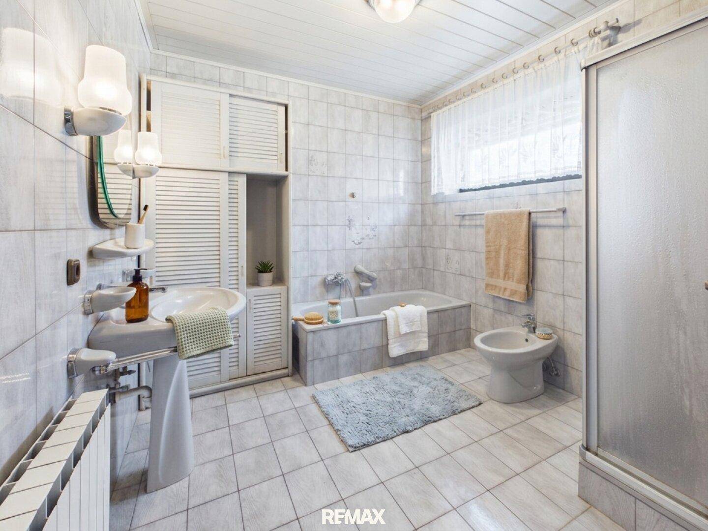 Gefliestes Badezimmer im 80er-Jahre-Stil mit Badewanne, Dusche und Bidet.