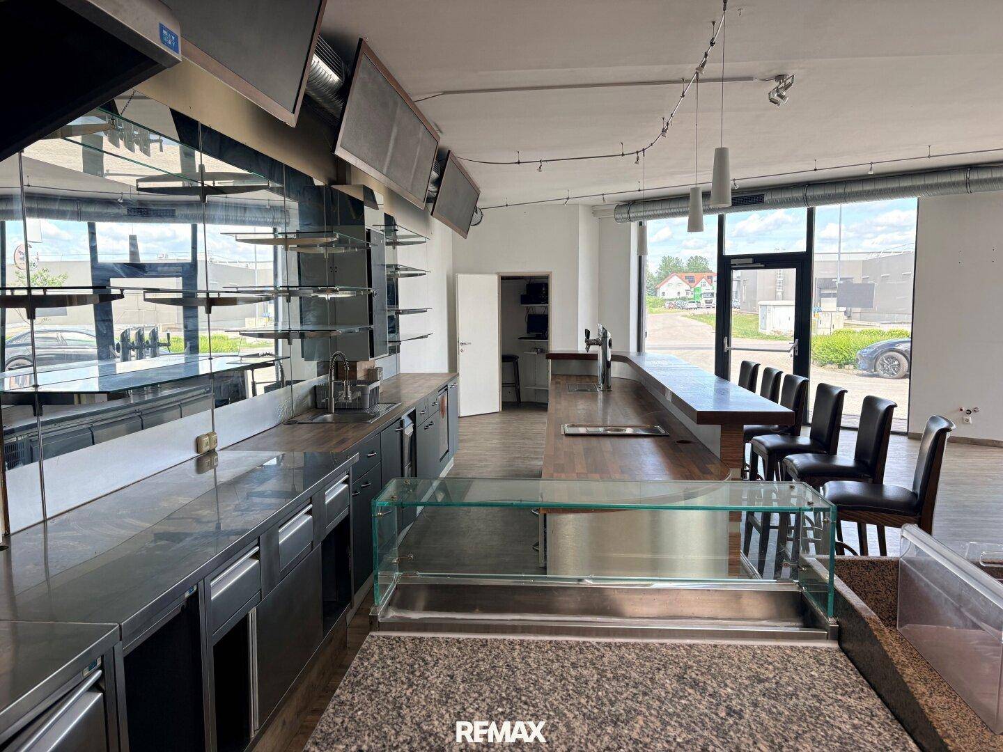 Innenansicht eines Barbereichs mit Theke, Kühlvitrine und Spiegelwand, ideal für Gastronomie und Kundenbedienung.