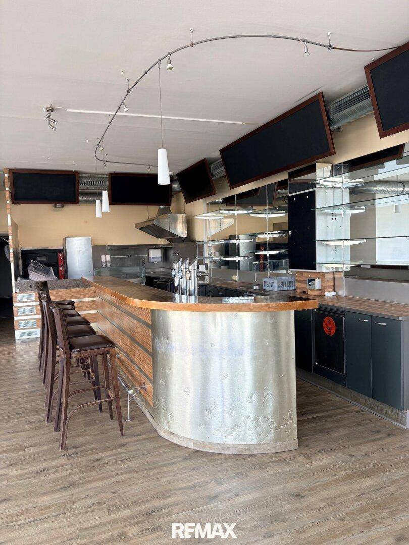 Geräumiger Barbereich mit Zapfanlage, Spiegelrückwand und mehreren Barhockern, bereit für Gäste und Service.