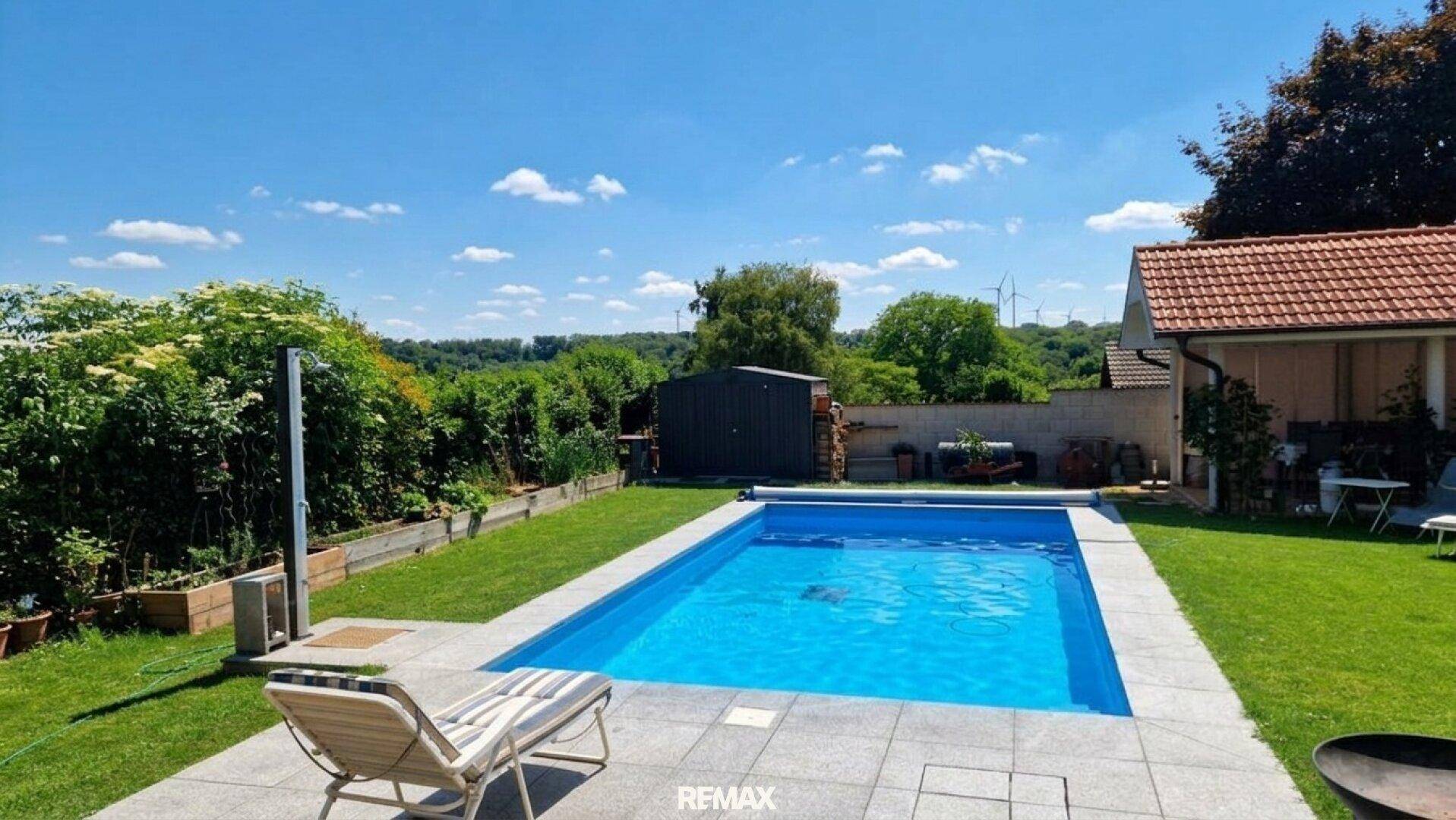 Entspannender Poolbereich im Garten mit Liegestuhl und Blick ins Grüne.