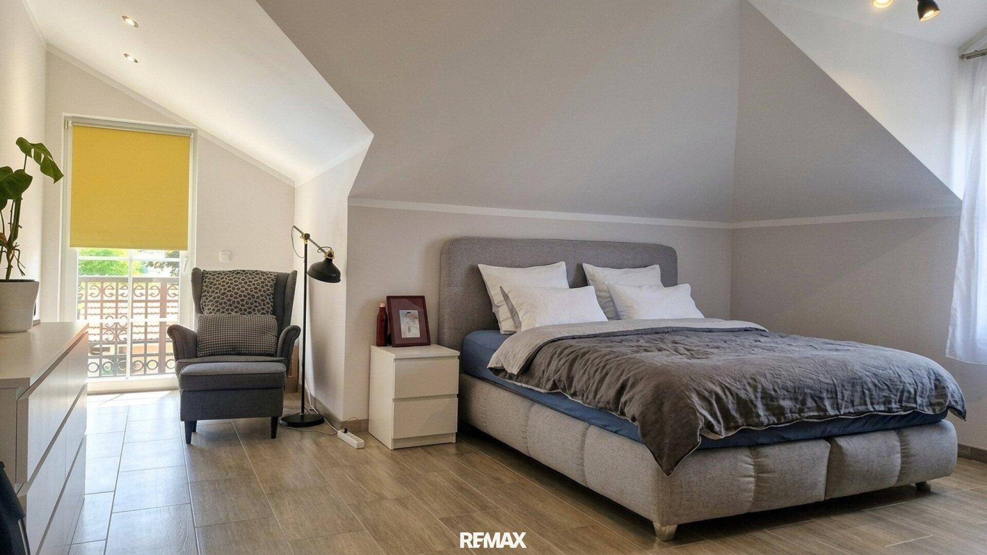 Helles Schlafzimmer im Dachgeschoss mit großem Bett und Zugang zum Balkon.