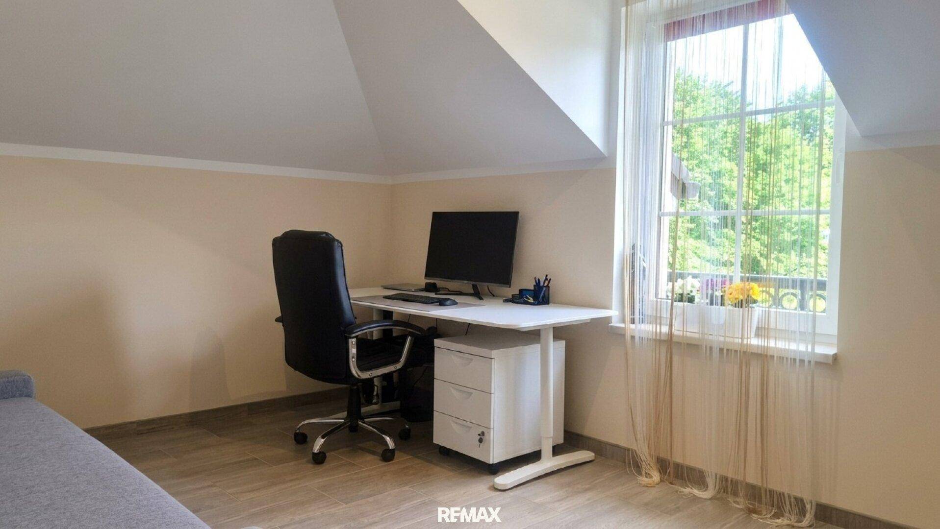 Ruhiges Arbeitszimmer im Dachgeschoss mit Schreibtisch und Fensterblick.