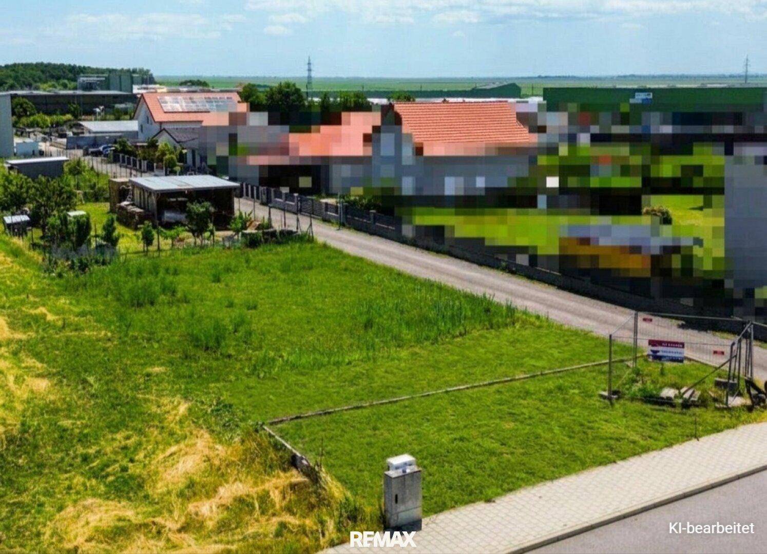 Luftaufnahme eines großen grünen Grundstücks mit angrenzender Straße und Wohnbebauung in der Ferne.