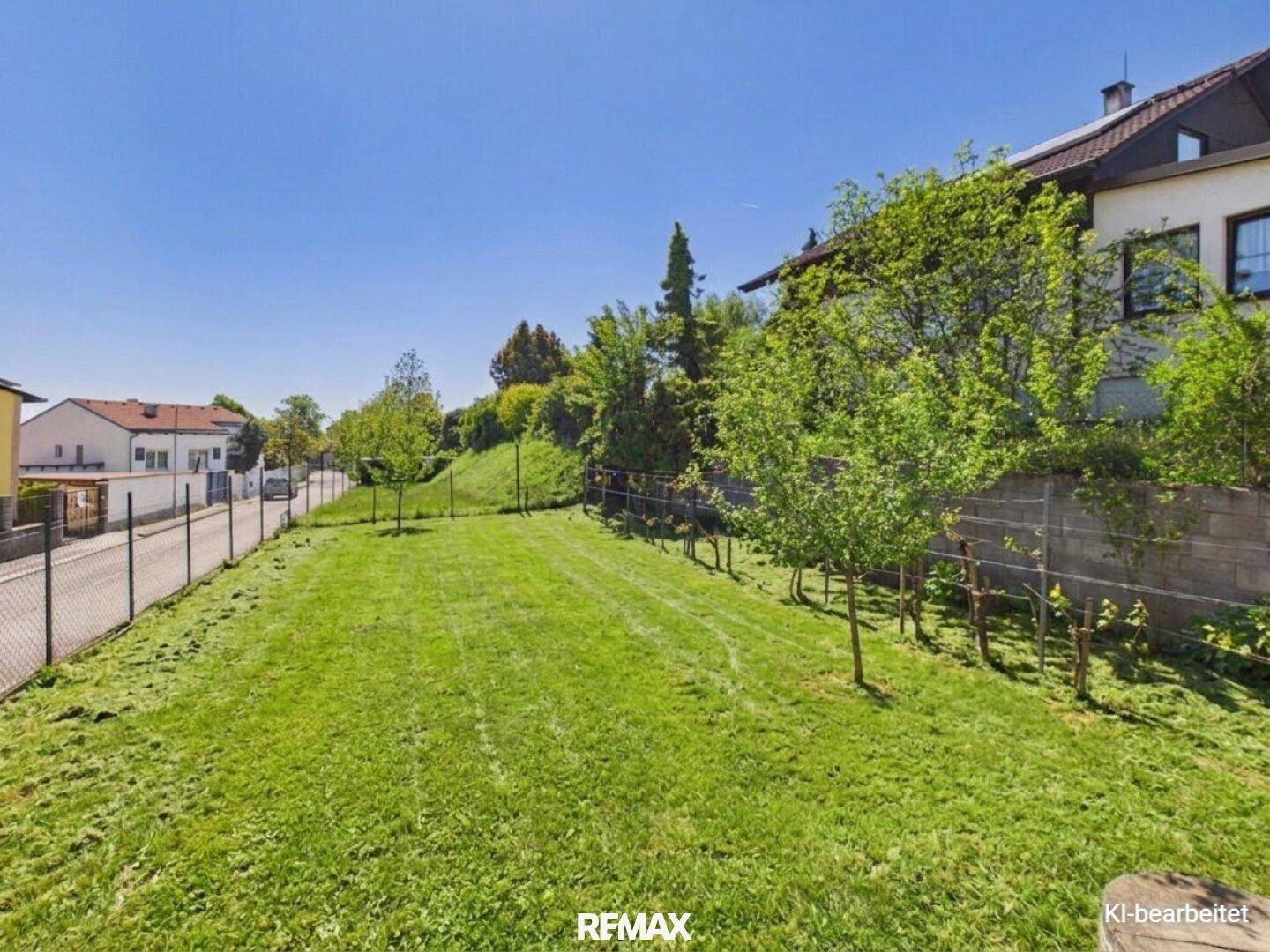 Weitläufiger Gartenbereich mit gepflegtem Rasen und jungen Bäumen unter blauem Himmel.