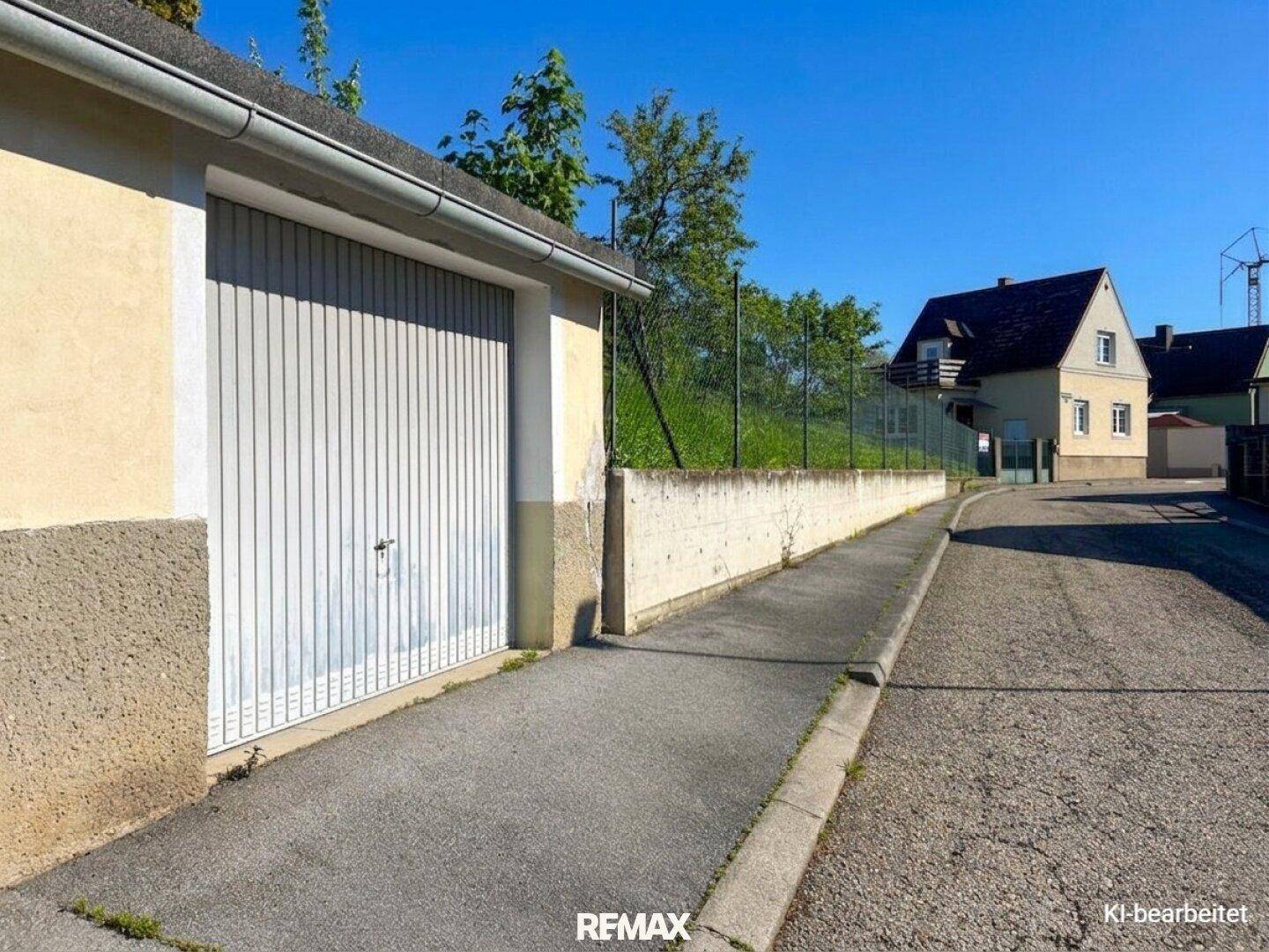 Garage mit Rolltor und Zufahrt von der Straße, neben dem Haus gelegen.