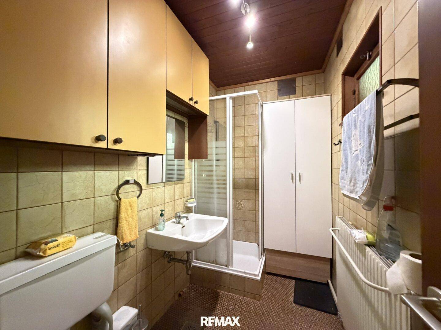 Funktionales Badezimmer mit Dusche, WC, Waschbecken und Fenster für Tageslicht.