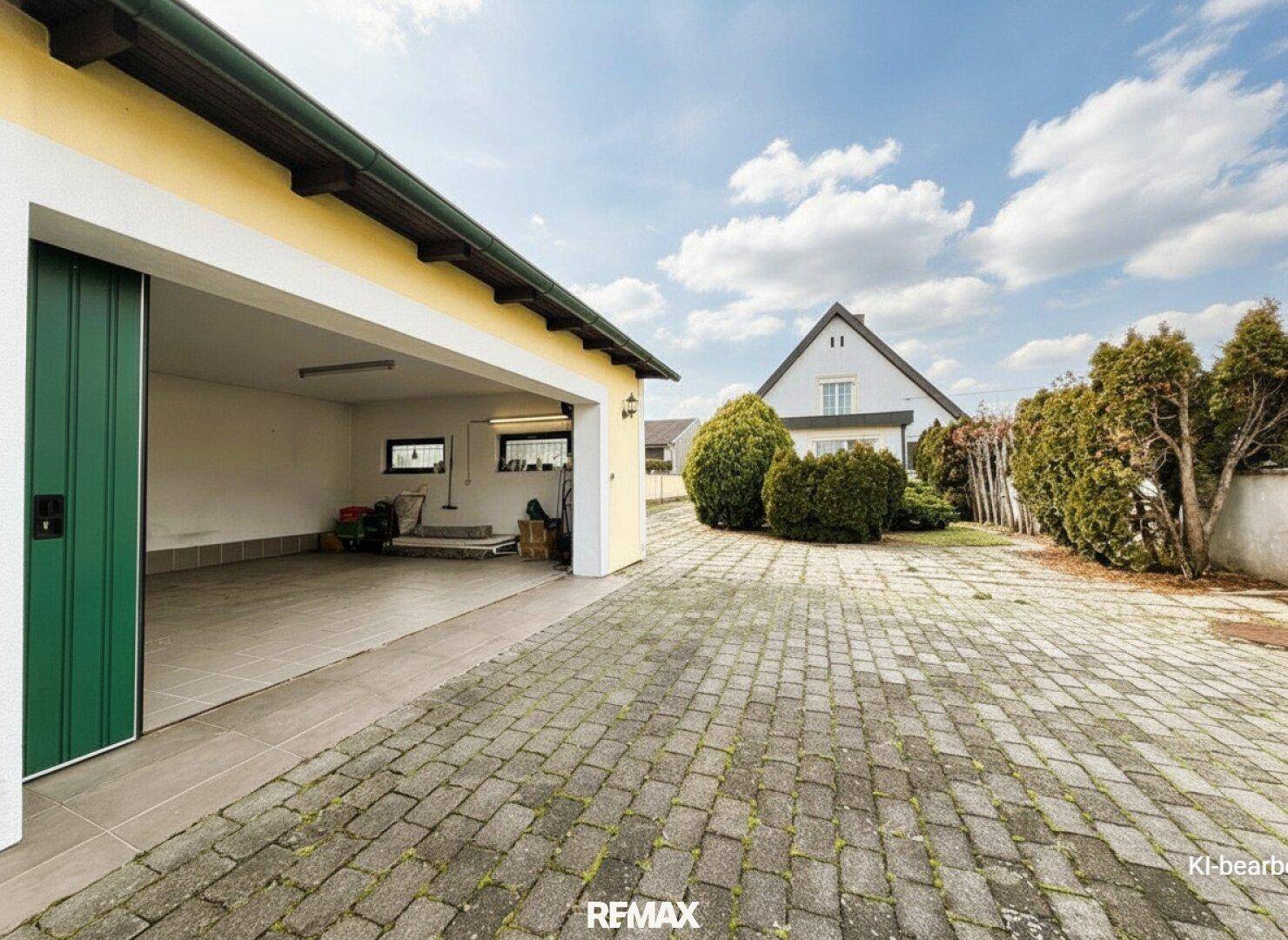 Geräumige Doppelgarage mit grünem Tor und gepflasterter Zufahrt zum Haupthaus.