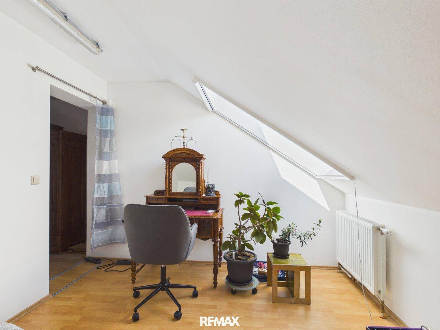 Helles Arbeitszimmer im Dachgeschoss mit Schreibtisch, Dachfenster und Pflanzen.
