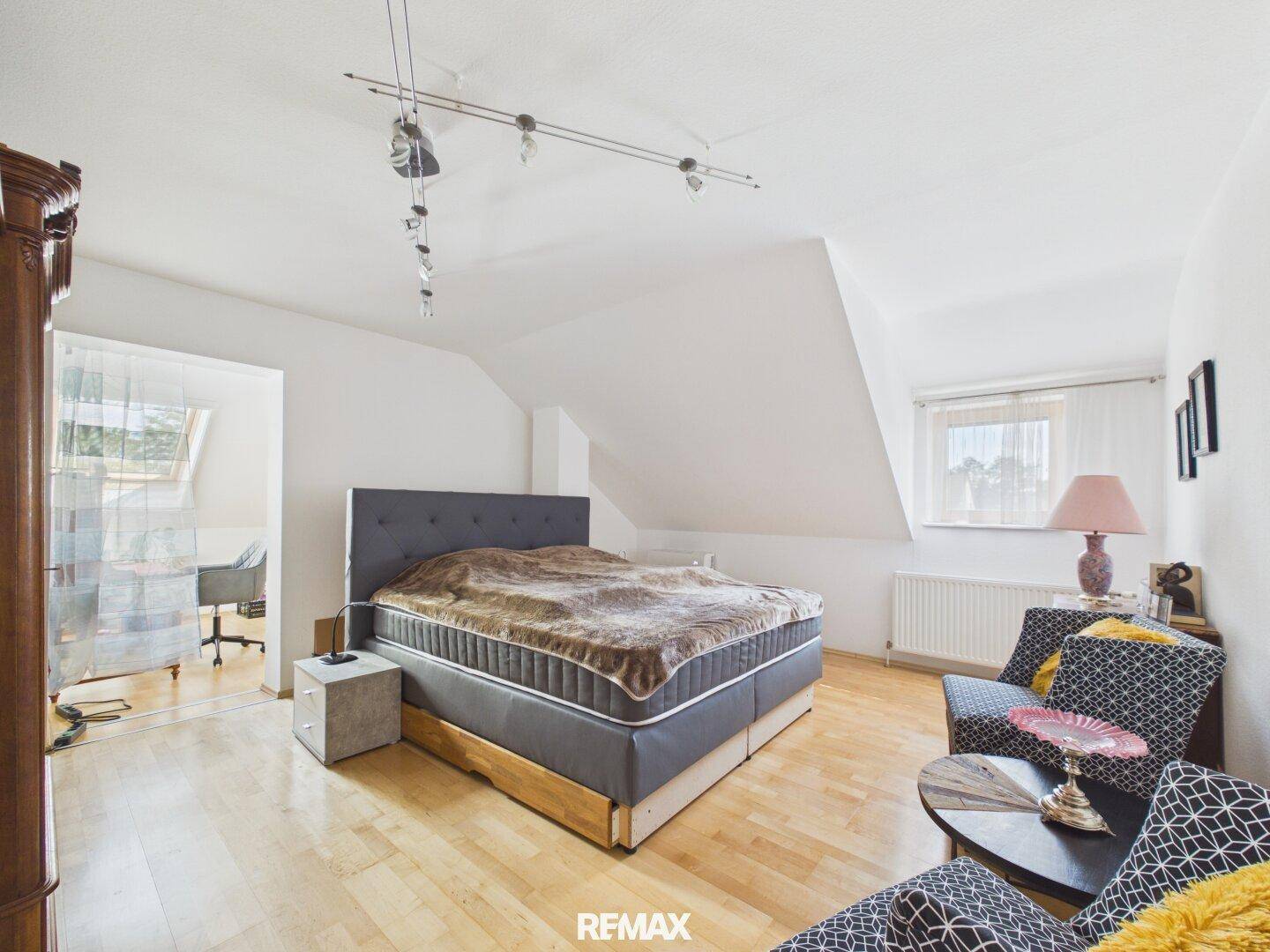 Gemütliches Schlafzimmer im Dachgeschoss mit Holzboden, Dachschräge und großem Bett.