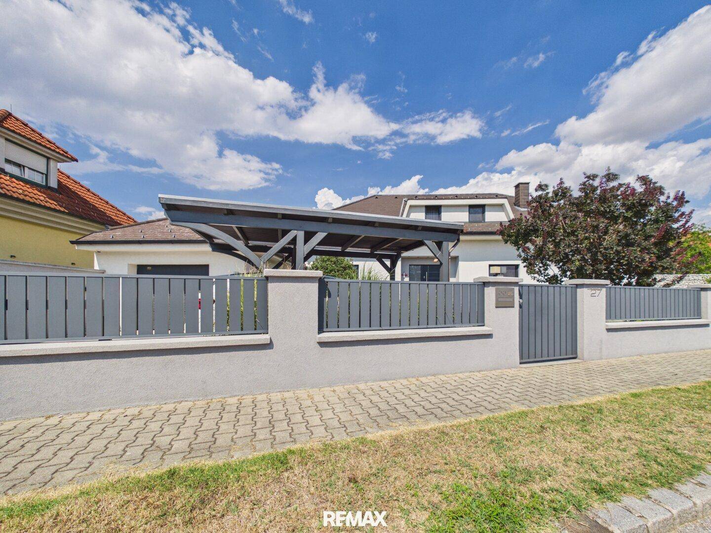 Gesamtansicht des Hauses mit Carport und modernem Zaun von der Straßenseite.