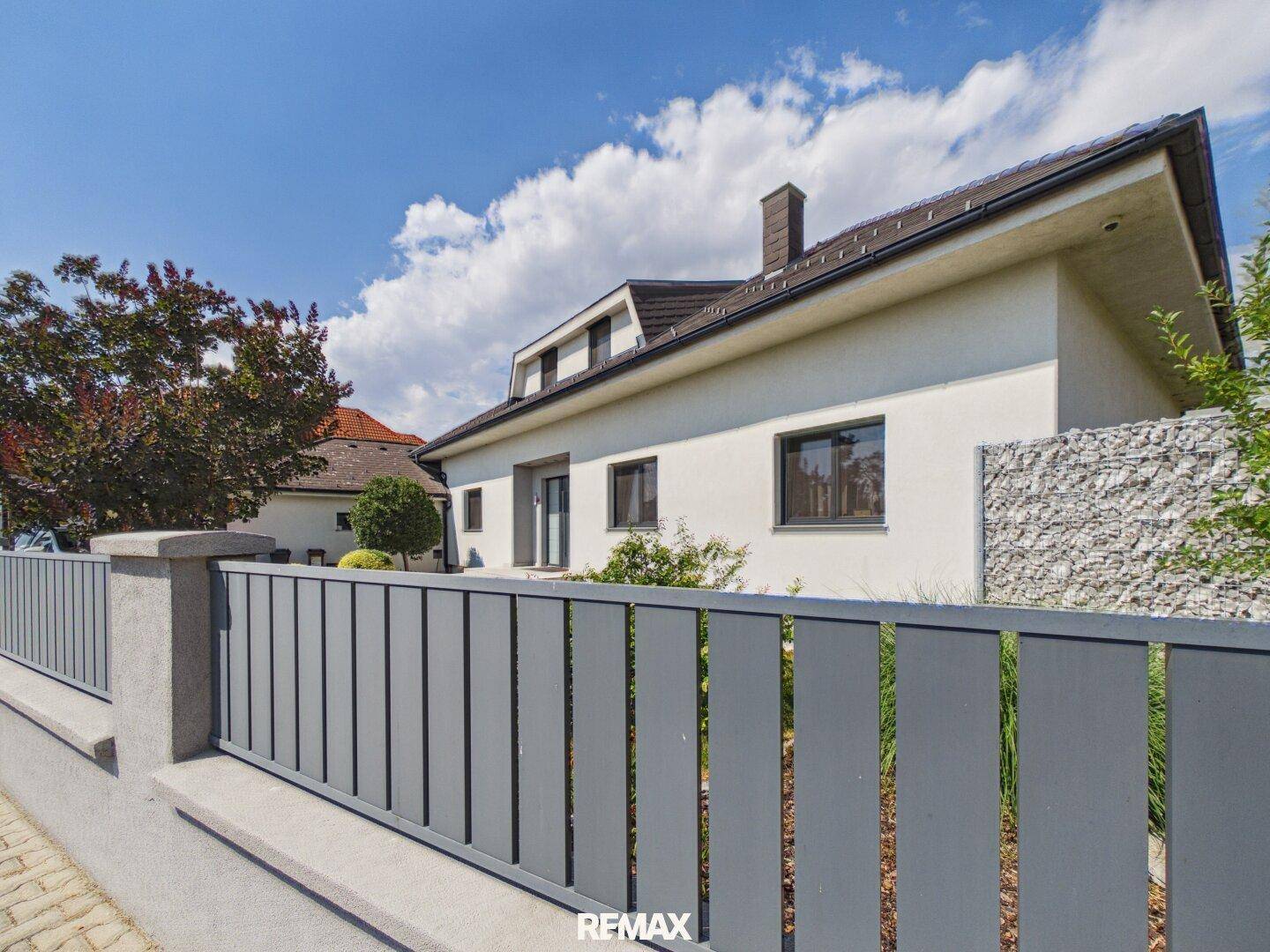 Ansicht des Hauses von der Straße mit modernem Zaun und gepflegter Fassade.