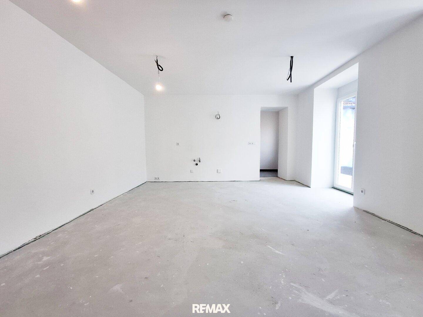 Heller, leerer Raum mit weißen Wänden und Betonboden, vorbereitet für die Installation einer Küche.