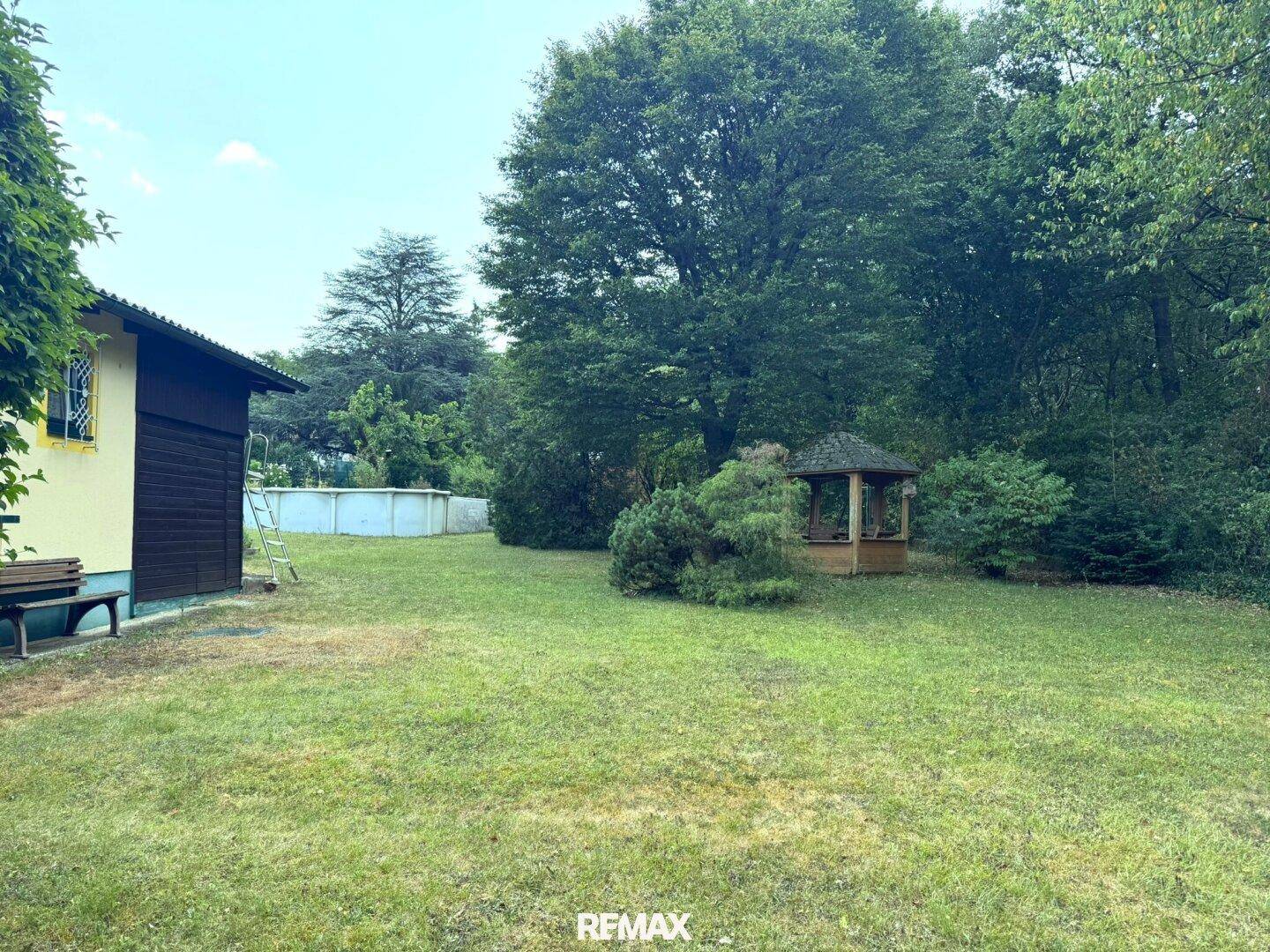 Großer Gartenbereich mit Aufstellpool, Holzpavillon und viel Grünfläche.