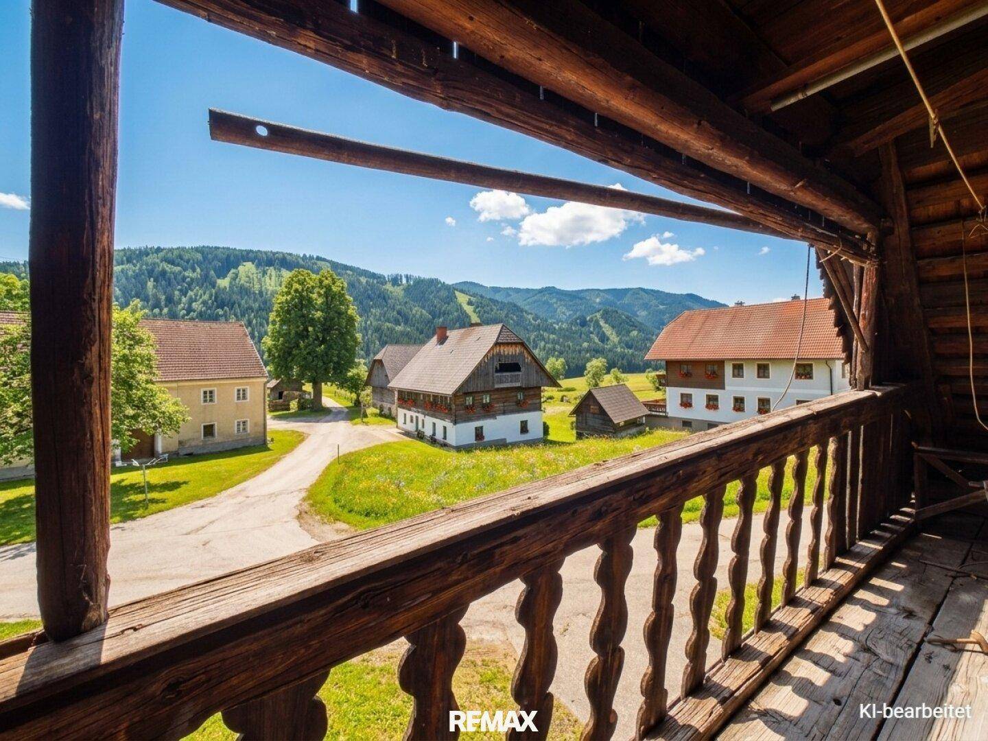 Rustikaler Holzbalkon mit weitem Blick über die hügelige Landschaft und andere Häuser.