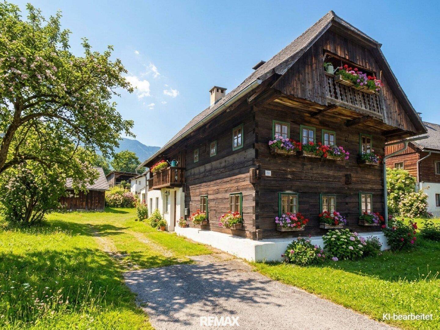 Traditionelles Holzhaus mit Blumenkästen und gepflegtem Vorgarten in sonniger Lage.