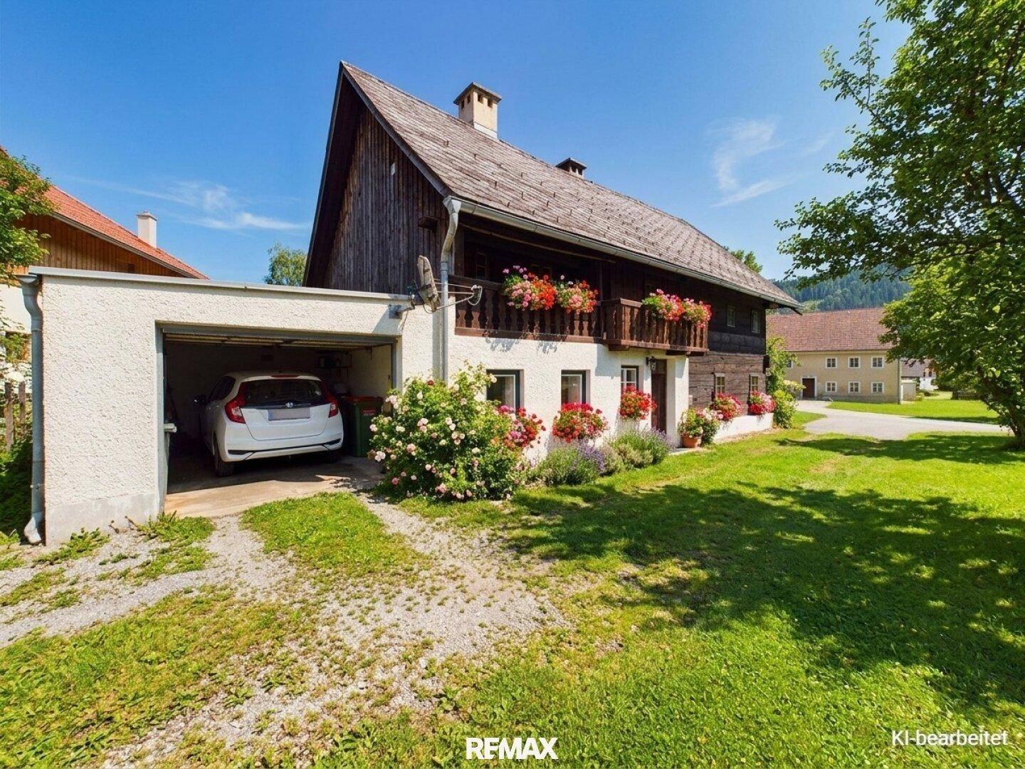 Traditionelles Holzhaus mit angrenzender Garage und gepflegtem Vorgarten.