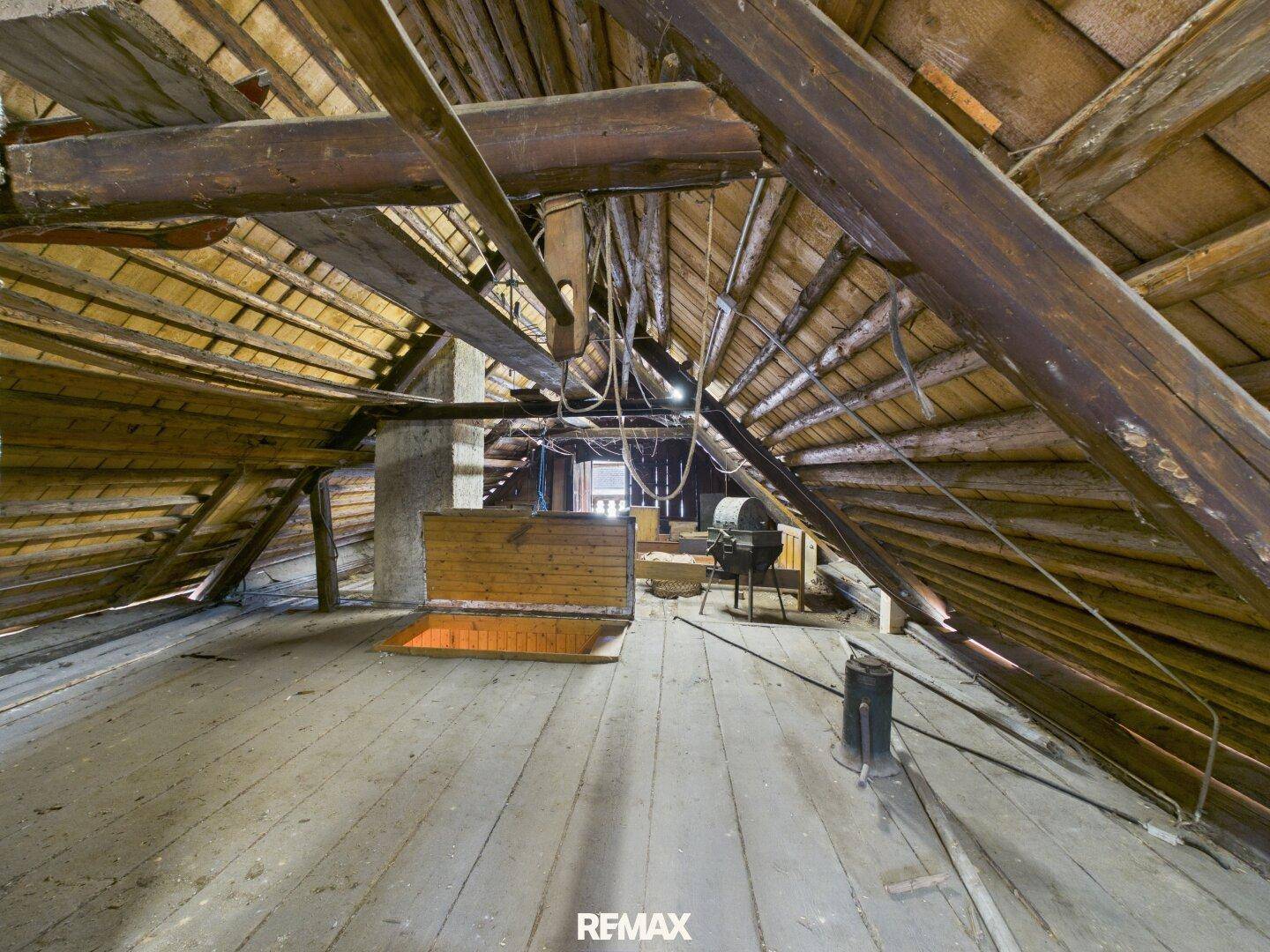 Geräumiger Dachboden mit sichtbaren Holzbalken und viel Stauraum, ideal für Ausbau.