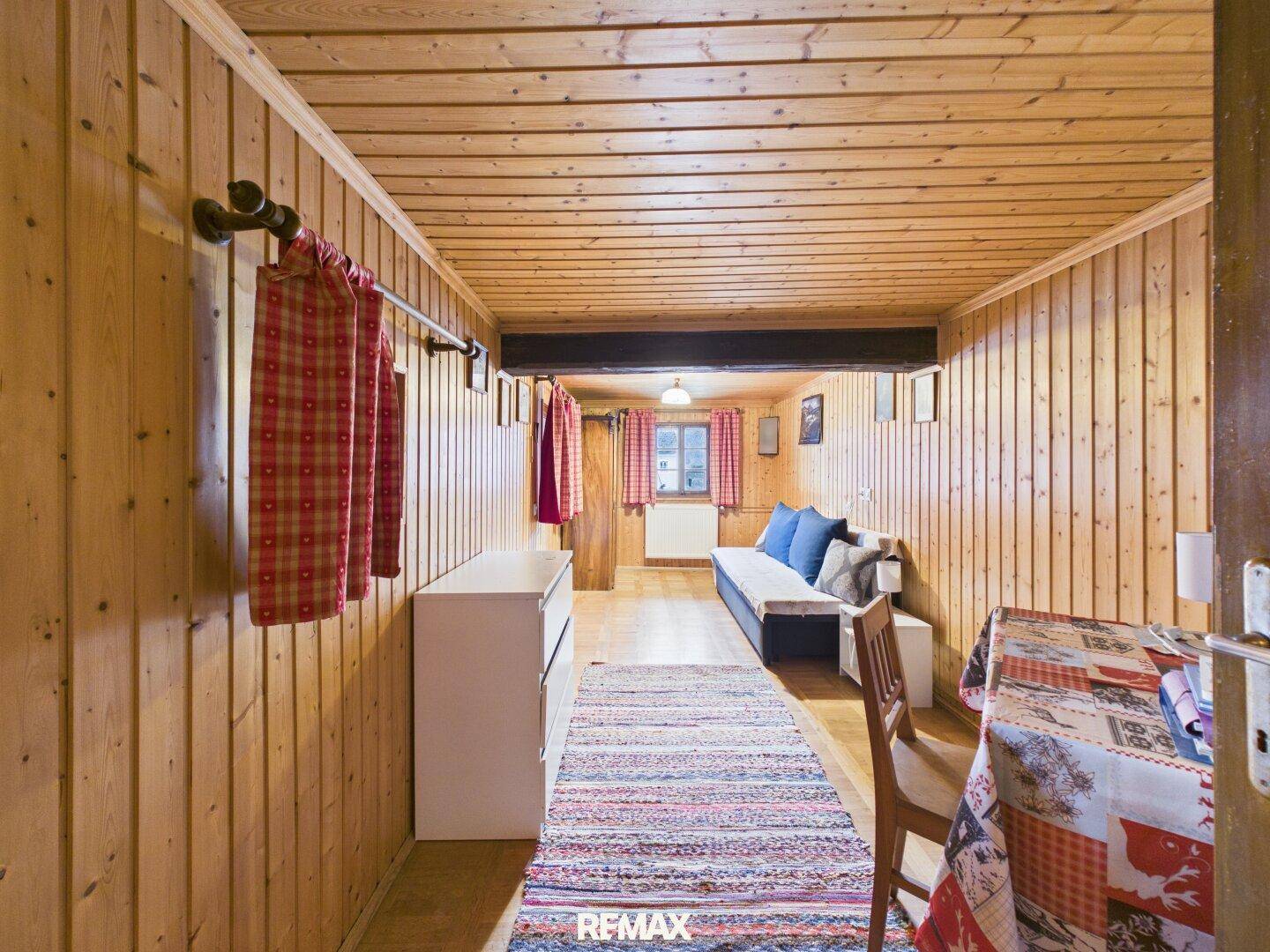 Gemütliches Schlafzimmer mit Holzvertäfelung, Holzboden und traditionellen Textilien.