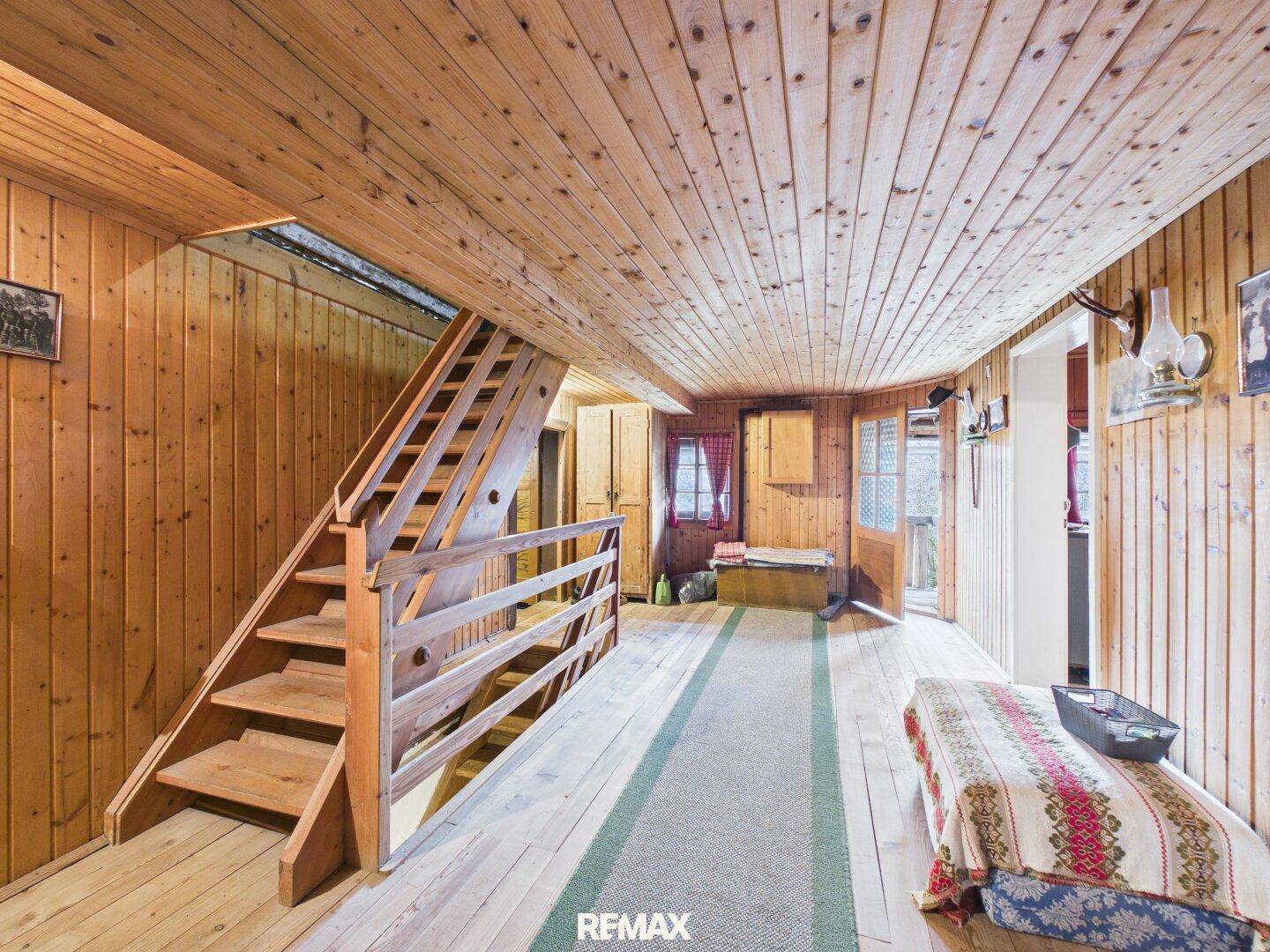 Heller Flur mit Holztreppe, Holzvertäfelung und Holzboden, typisch für ein Landhaus.
