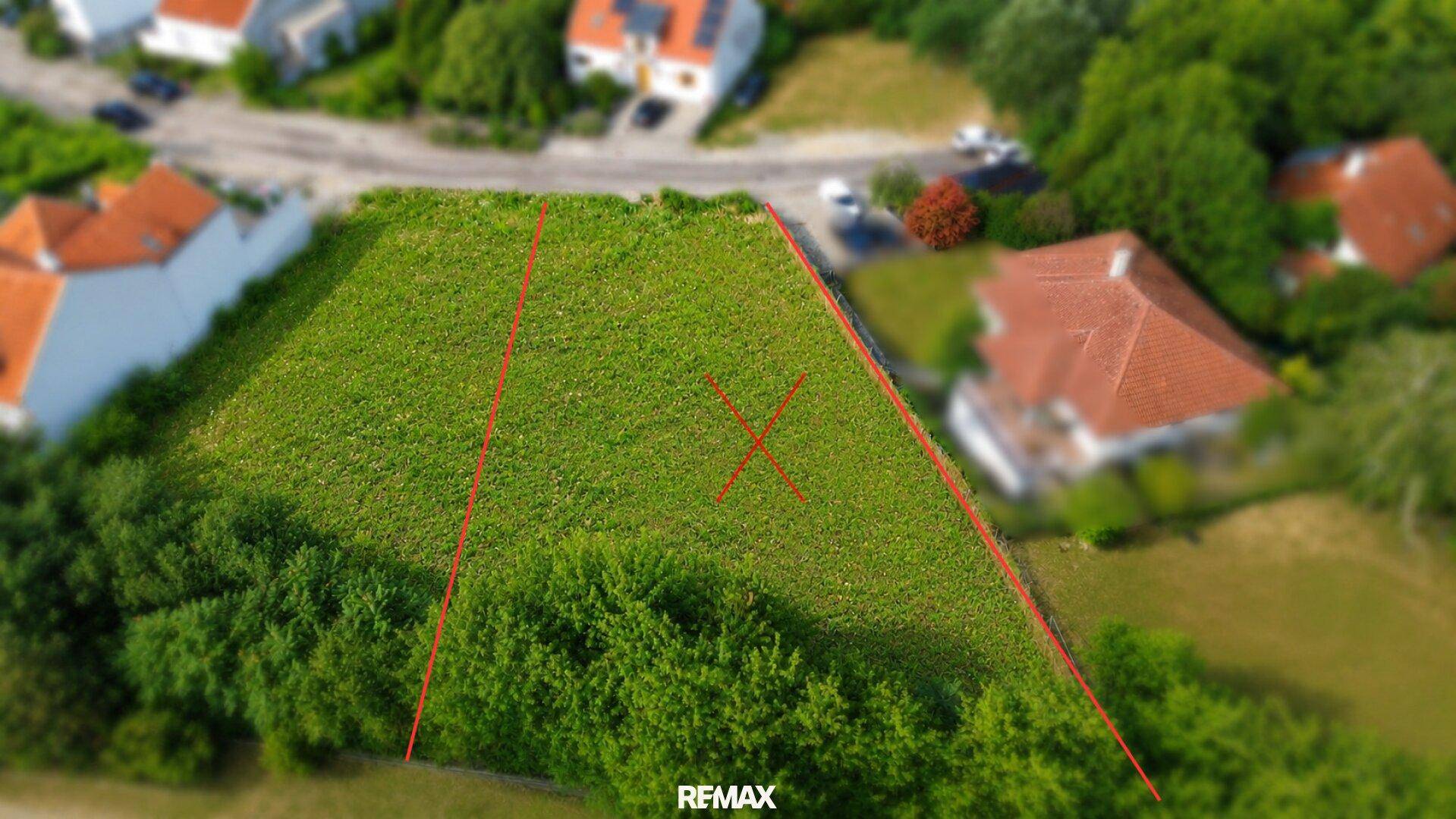 Weitläufige Luftaufnahme eines grünen Baugrundstücks mit Markierungen, eingebettet in eine grüne Wohnsiedlung.